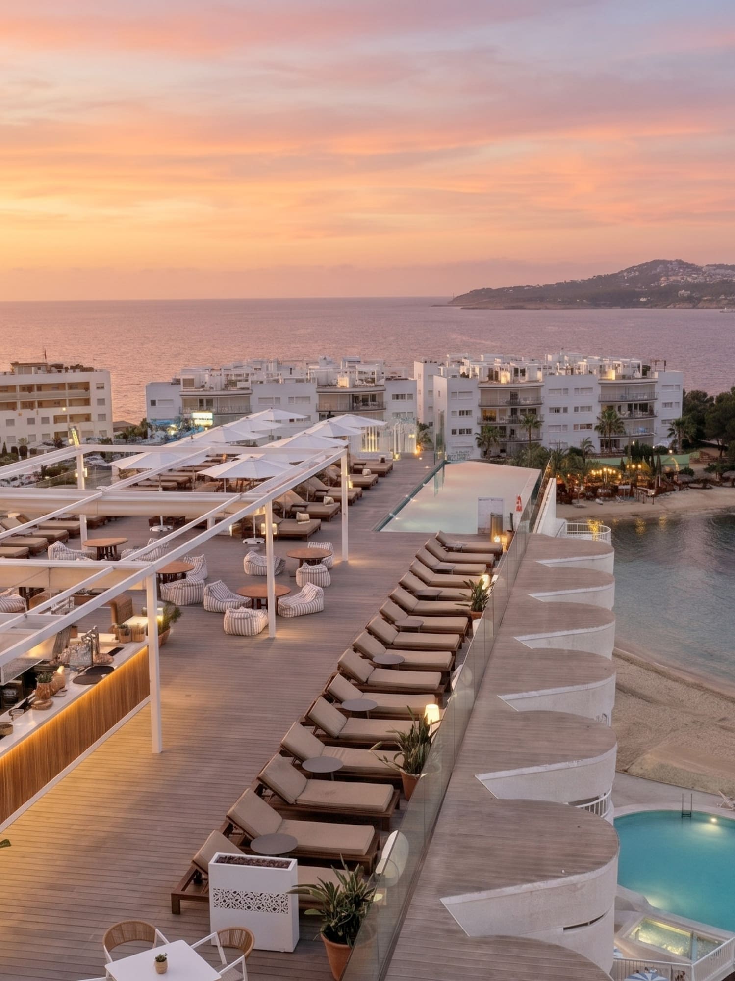 Coastal resort rooftop bar and pool at sunset, ocean and beach view.