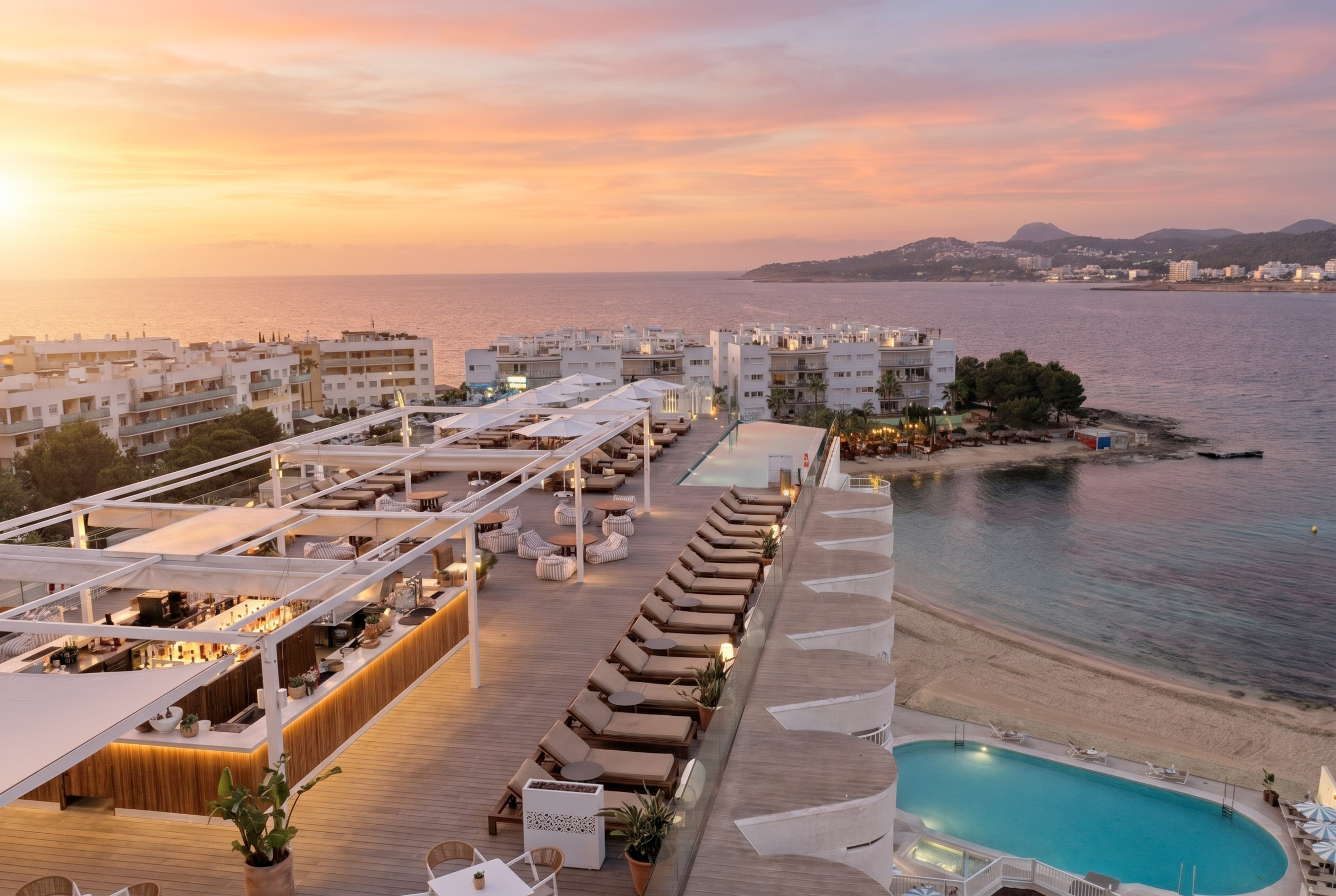 Coastal resort rooftop bar and pool at sunset, ocean and beach view.