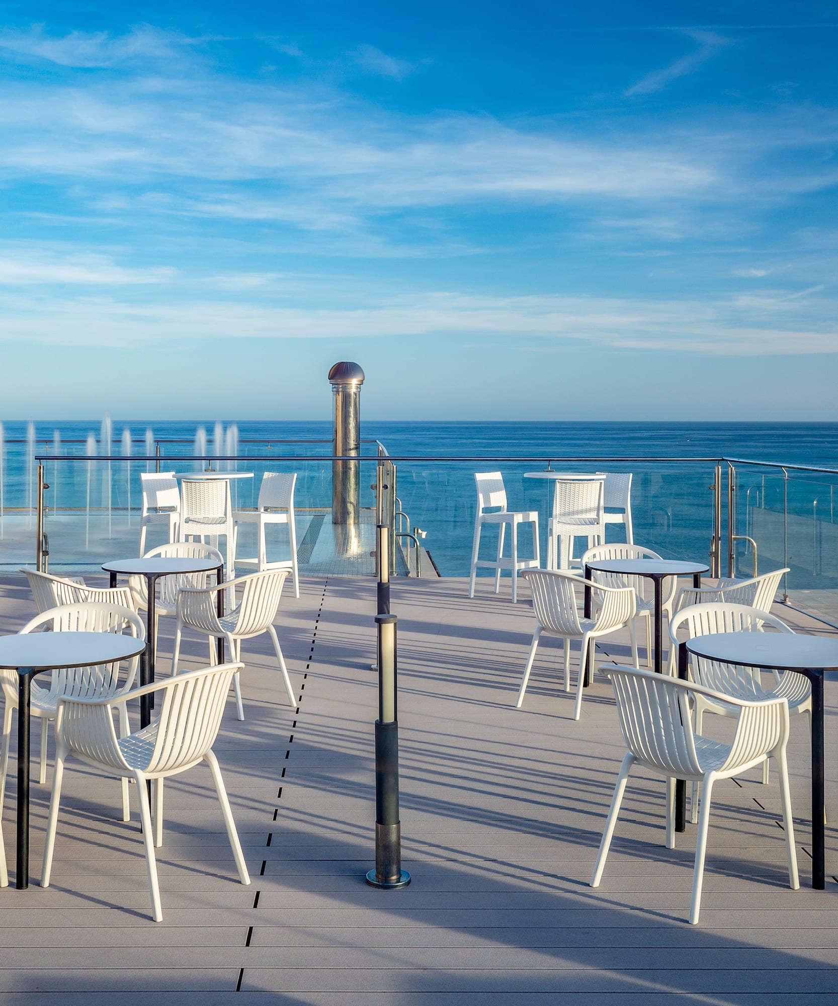 a patio with white chairs and a water fountain