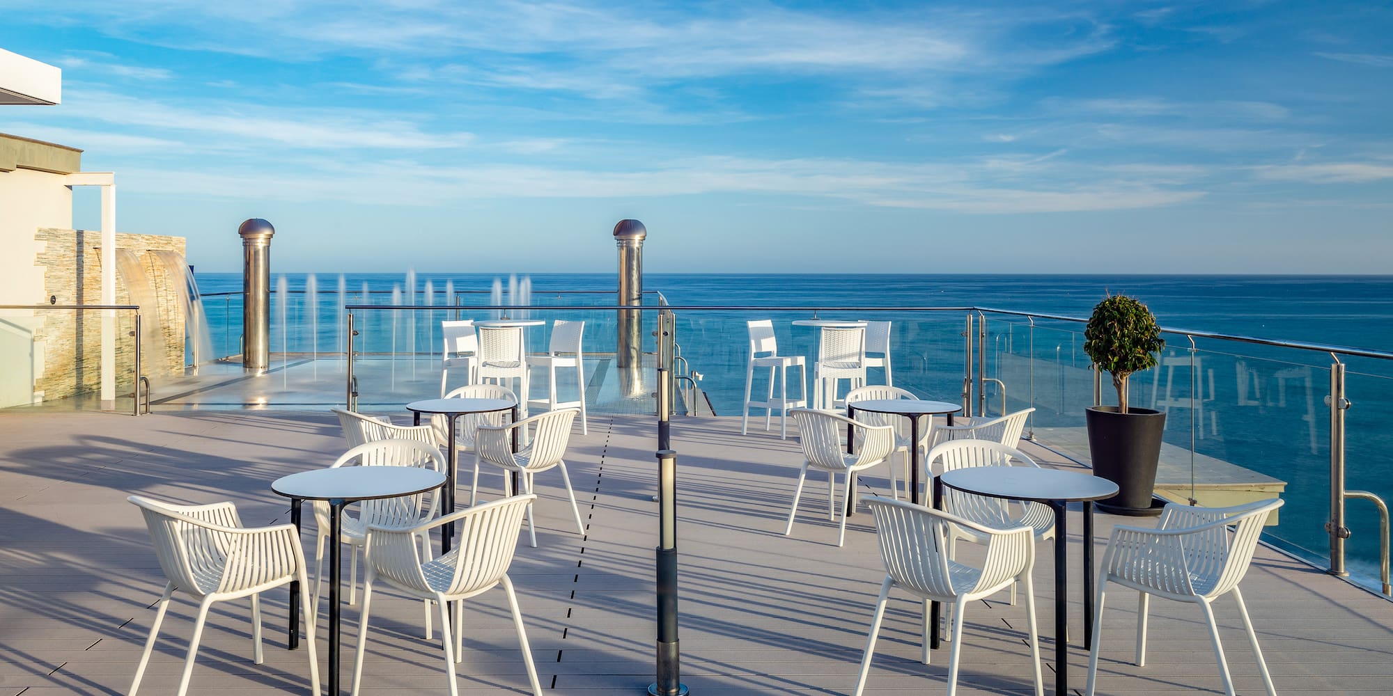 a patio with white chairs and a water fountain
