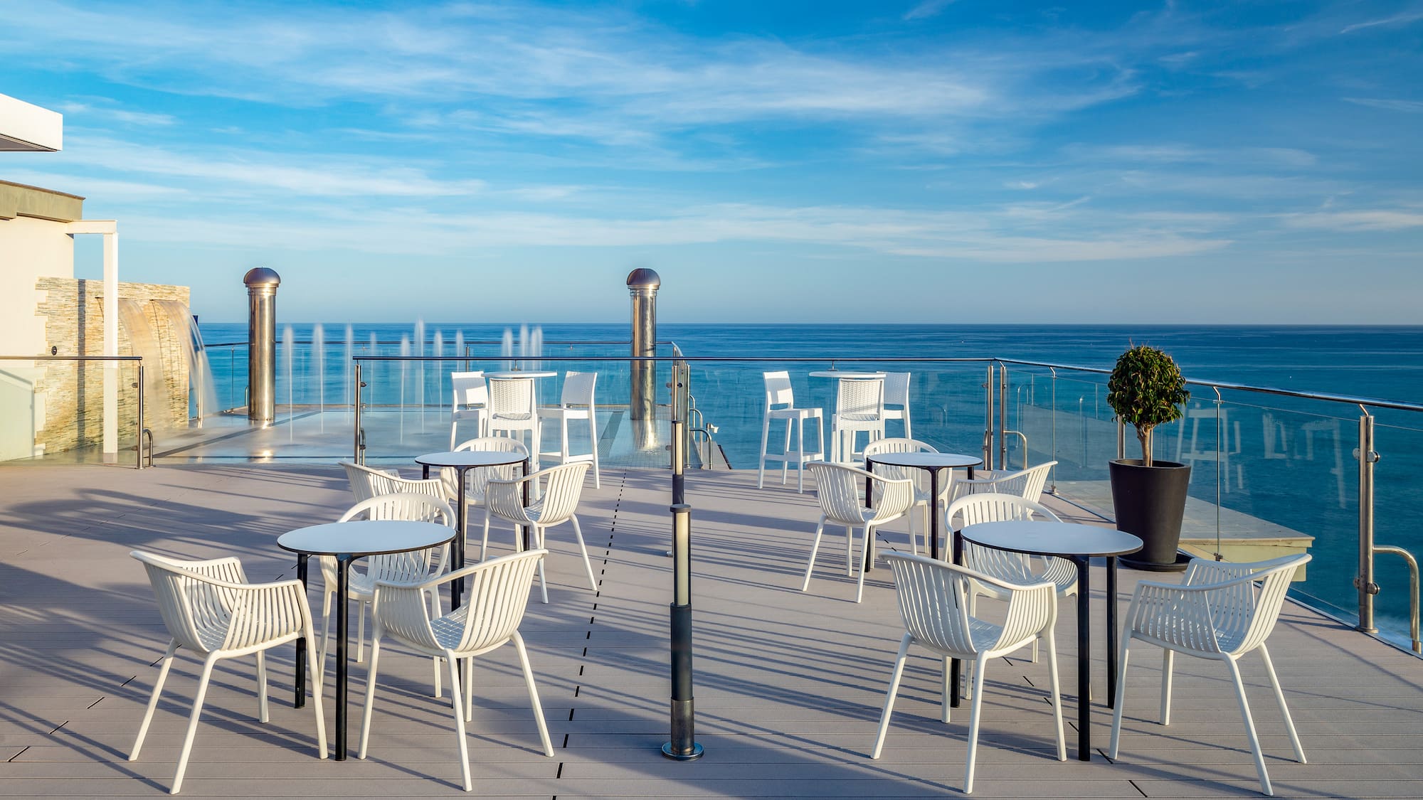 a patio with white chairs and a water fountain