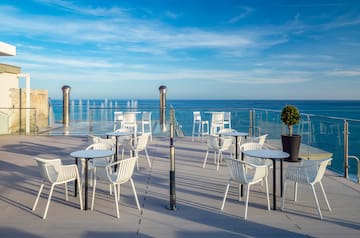 a patio with white chairs and a water fountain