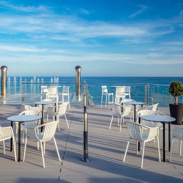 a patio with white chairs and a water fountain