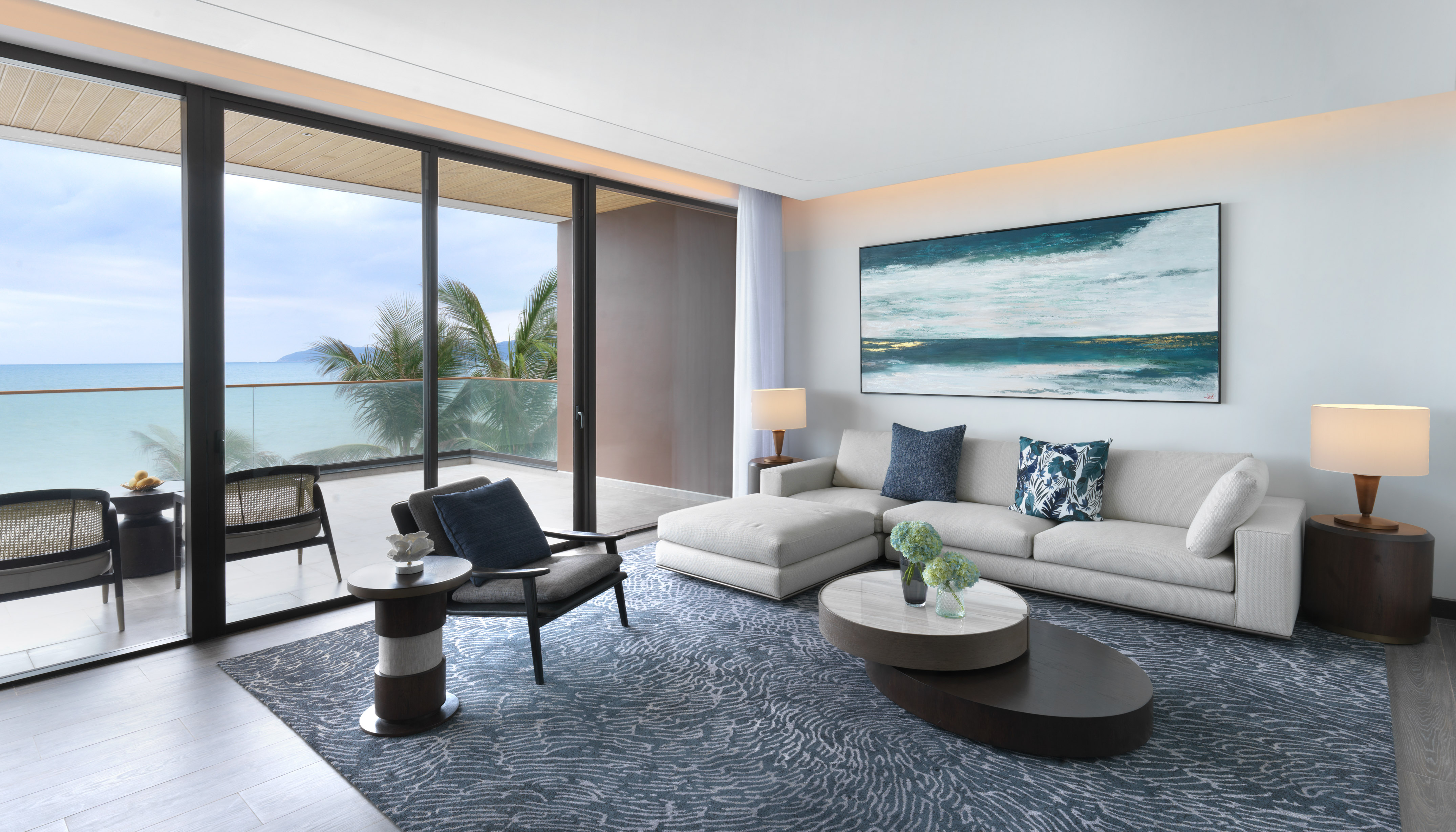 Modern luxury living room with ocean view, balcony, and abstract art.