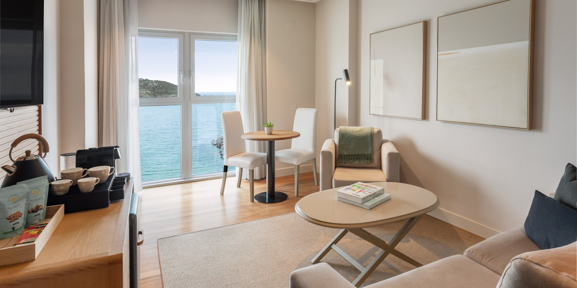 Luminosa suite de hotel moderna con vista al mar y sala de estar.