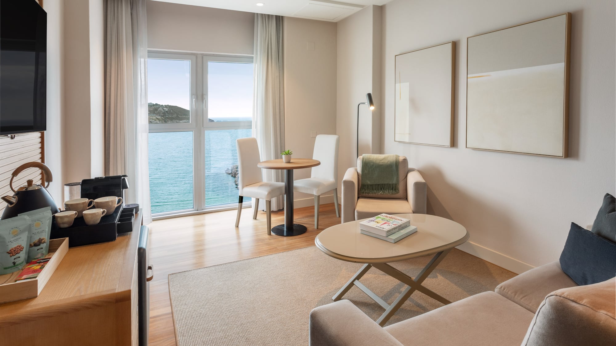 Luminosa suite de hotel moderna con vista al mar y sala de estar.