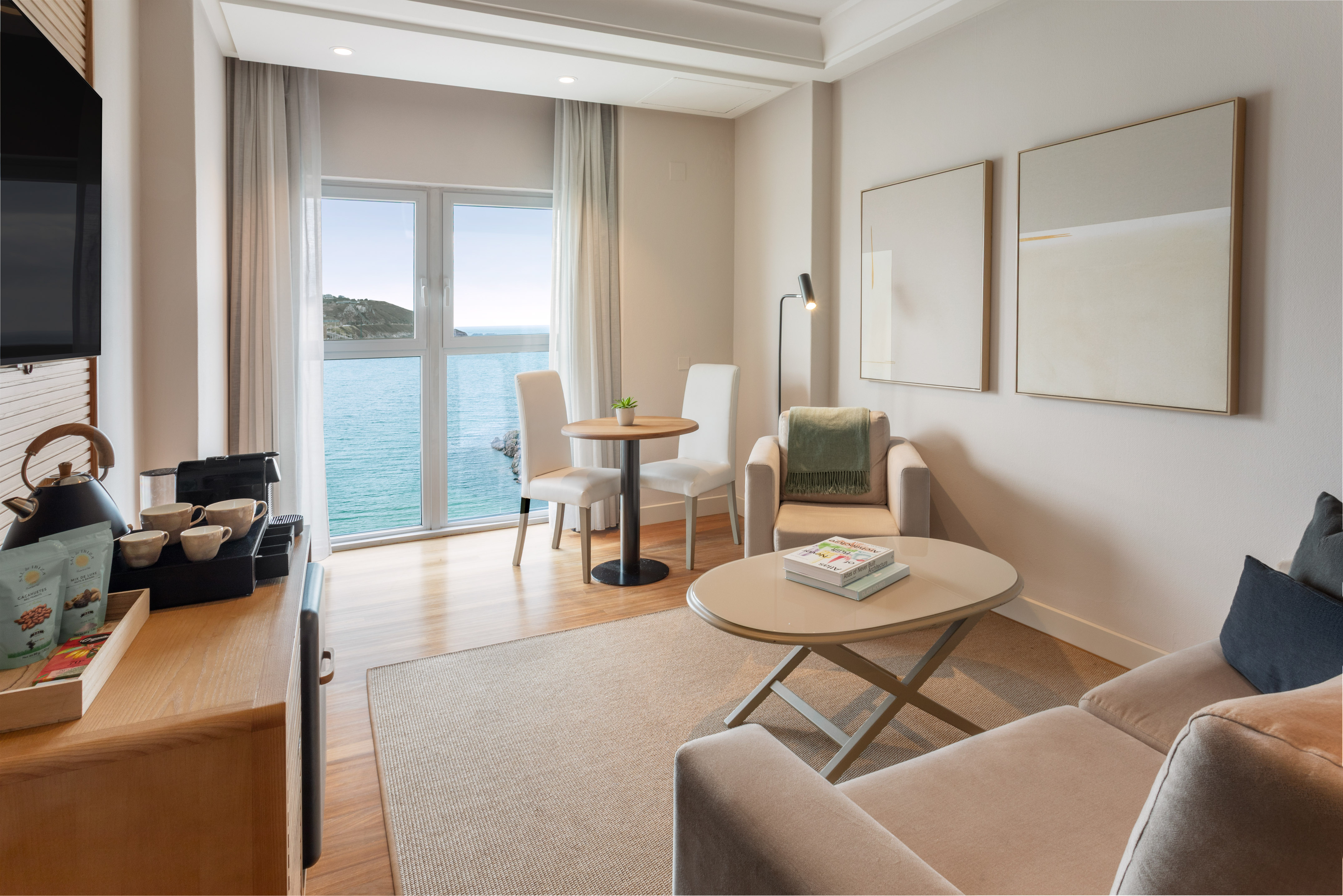 Luminosa suite de hotel moderna con vista al mar y sala de estar.