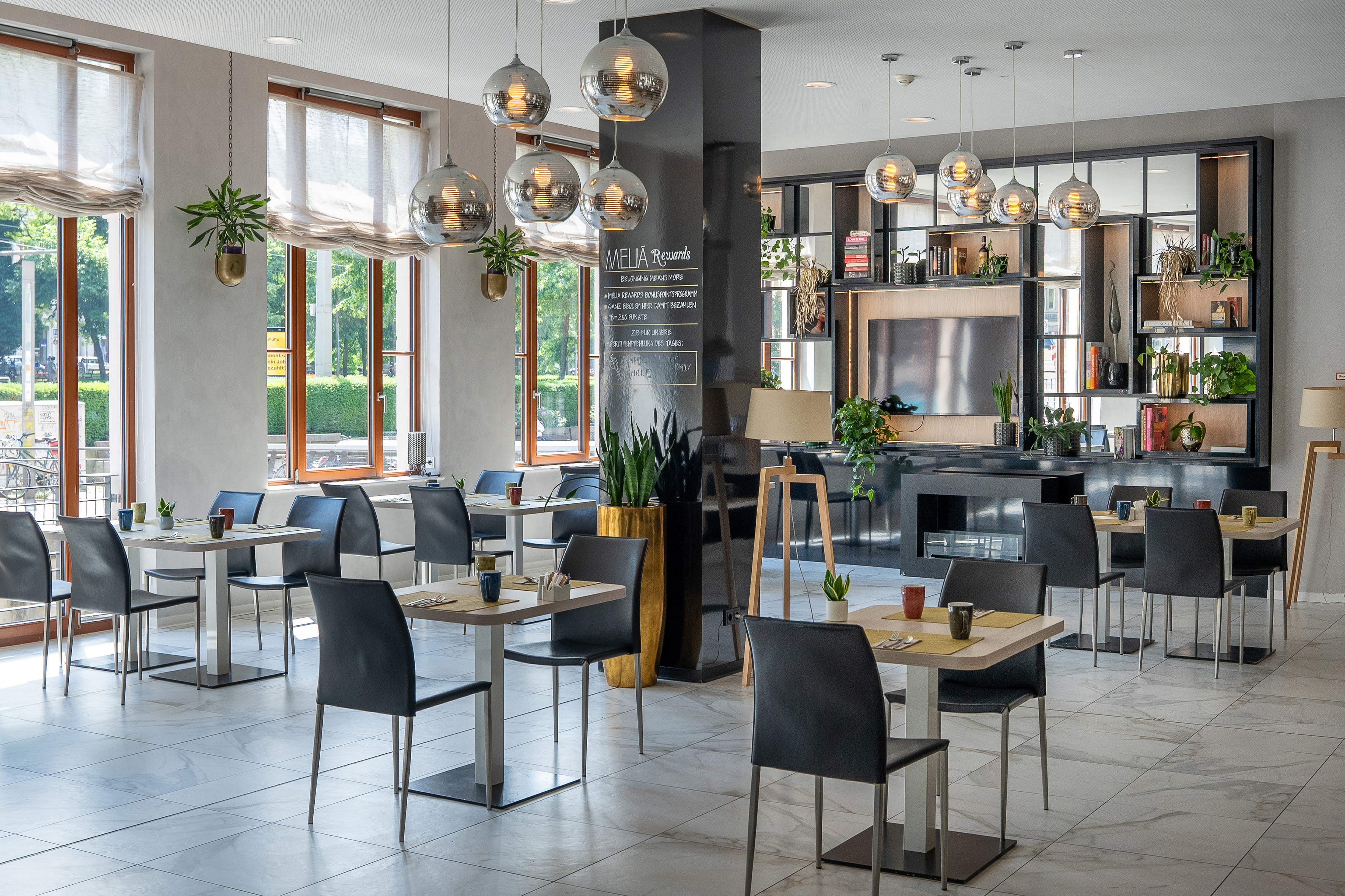 Modern Meliá hotel restaurant interior with set dining tables and green plants.