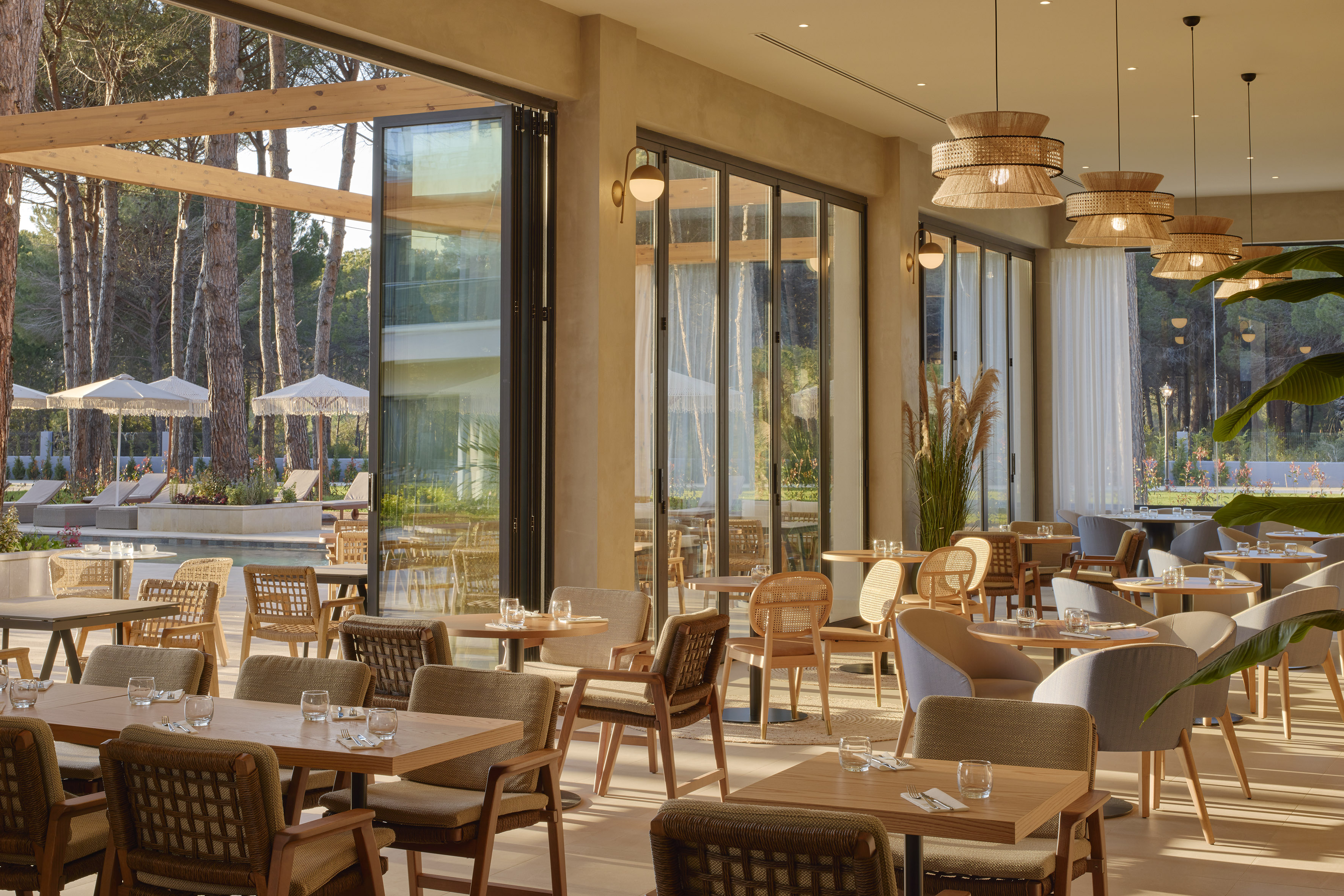 Stylish resort restaurant interior overlooking pool and pine forest patio.