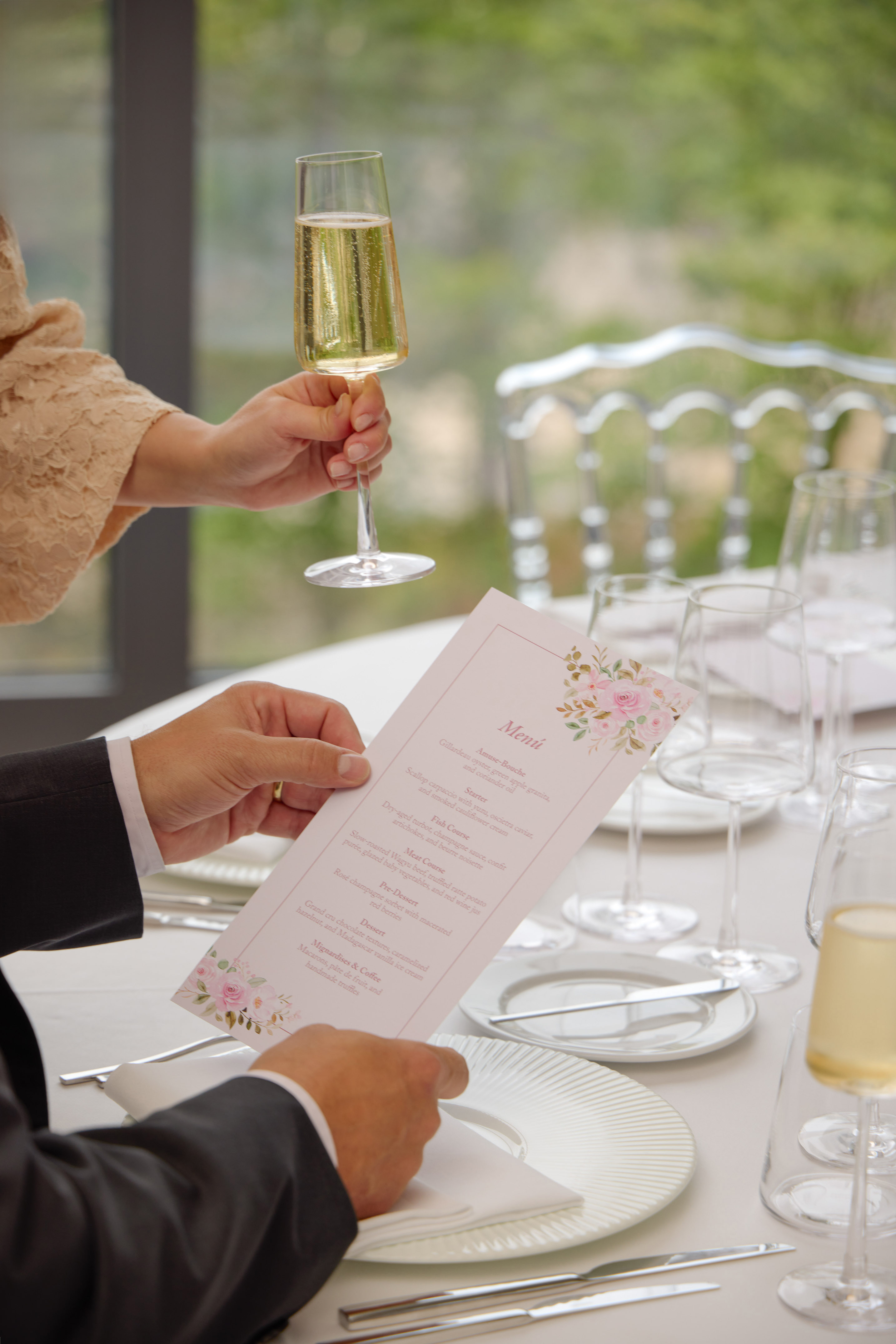 Guest holding champagne while reading a gourmet menu at a fine dining event.