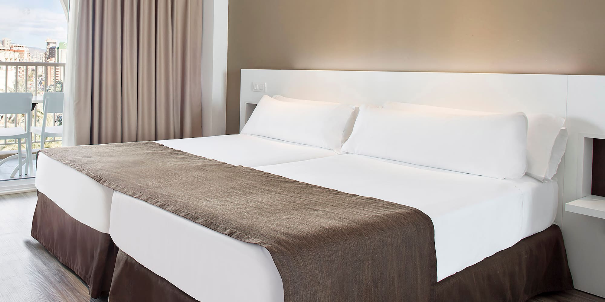 a bed with white sheets and brown blanket