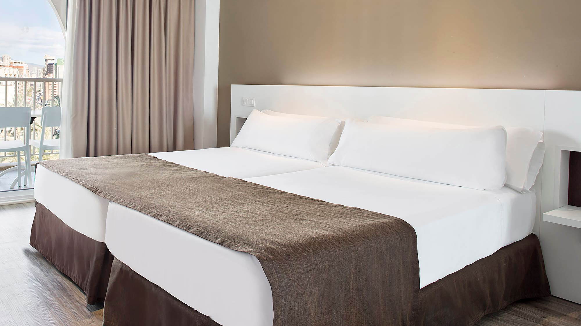 a bed with white sheets and brown blanket