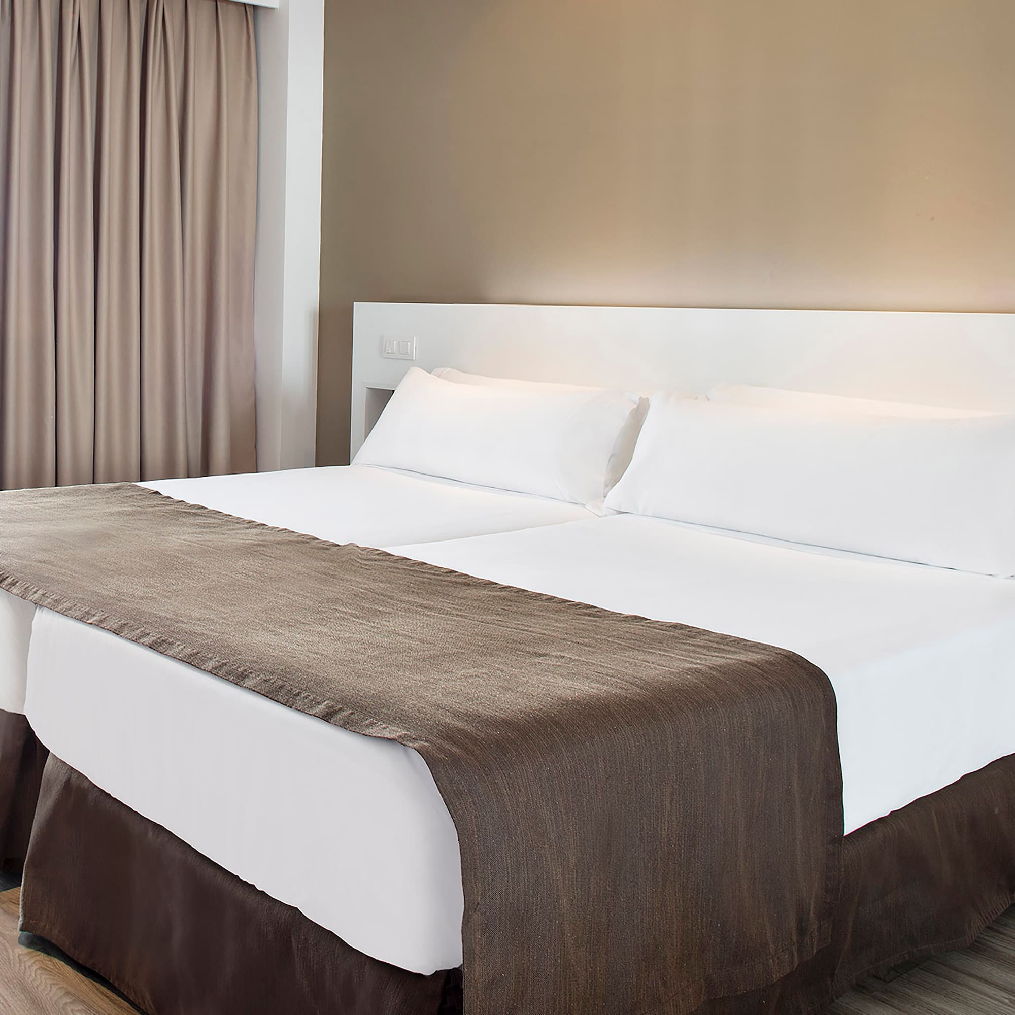 a bed with white sheets and brown blanket