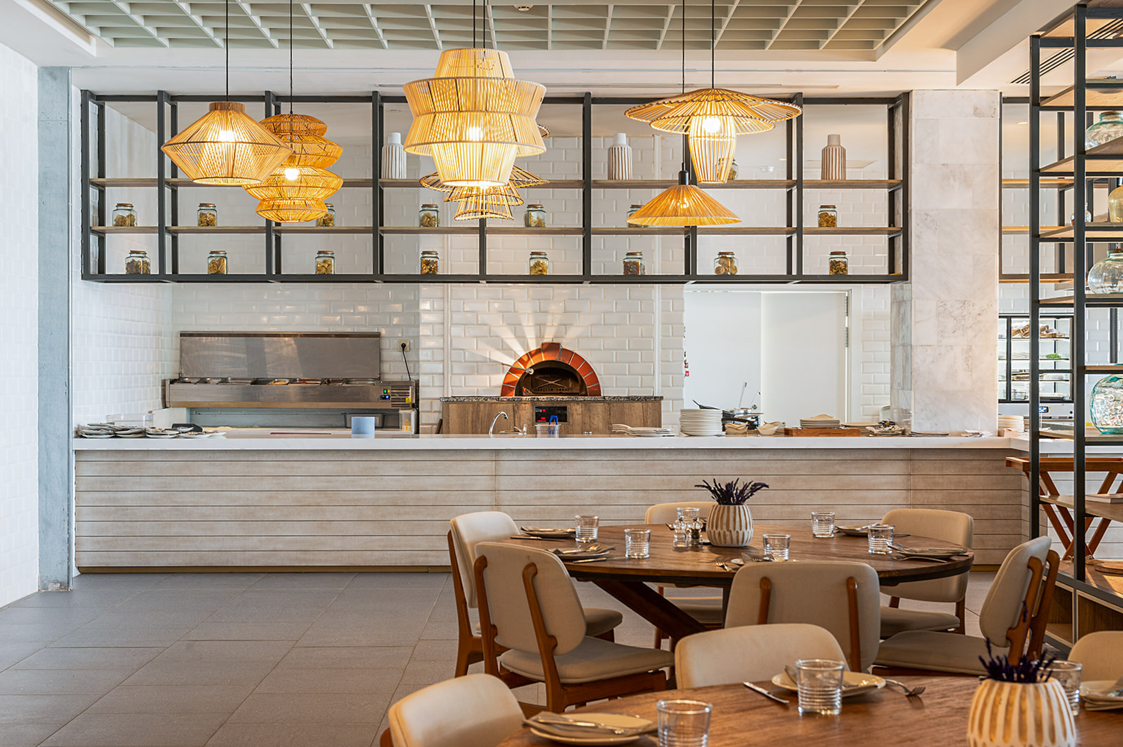 Modern restaurant interior, brick pizza oven, buffet, natural wood dining tables.