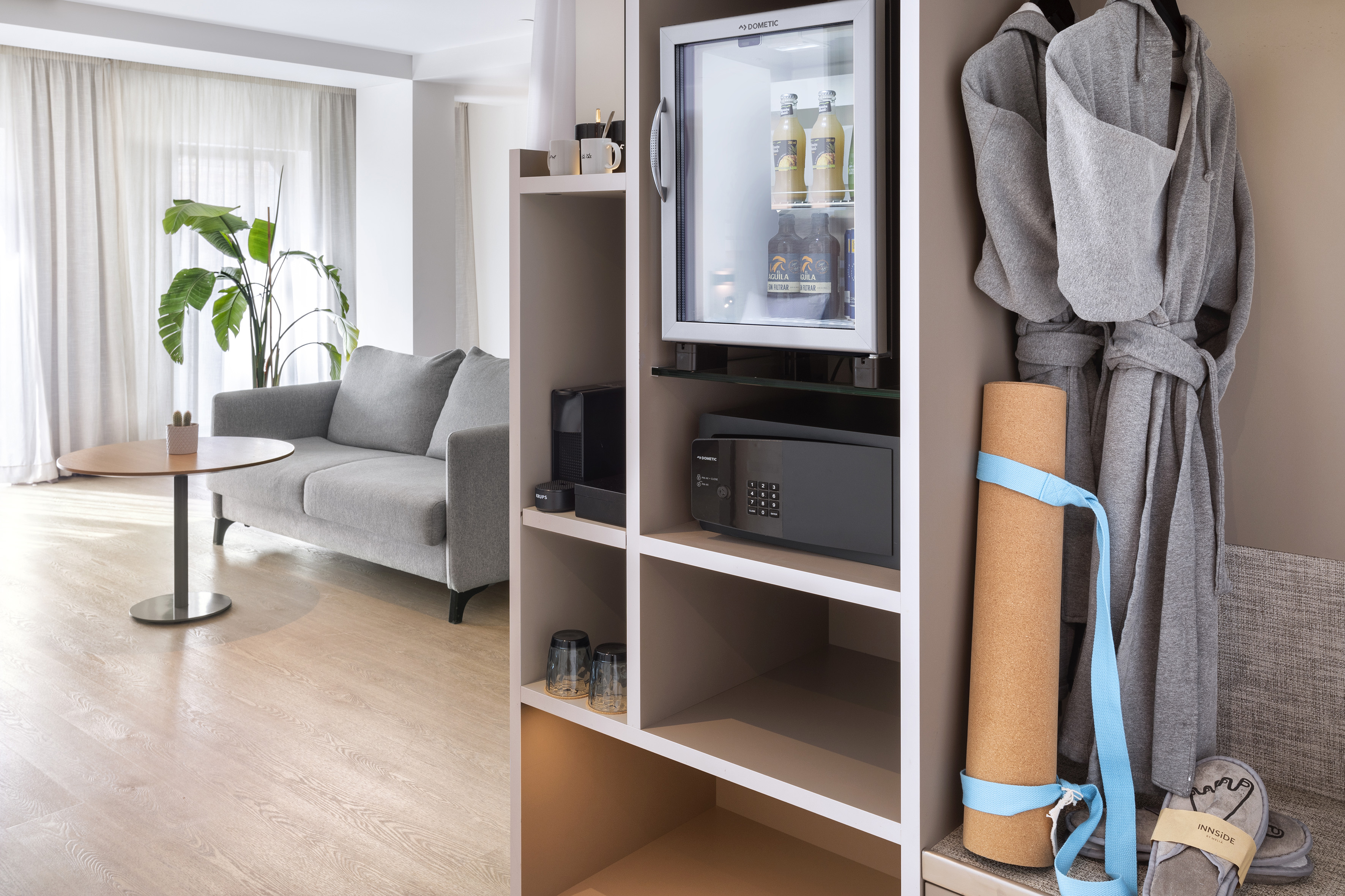 Suite de hotel moderna con sofá, minibar, caja fuerte y albornoces.