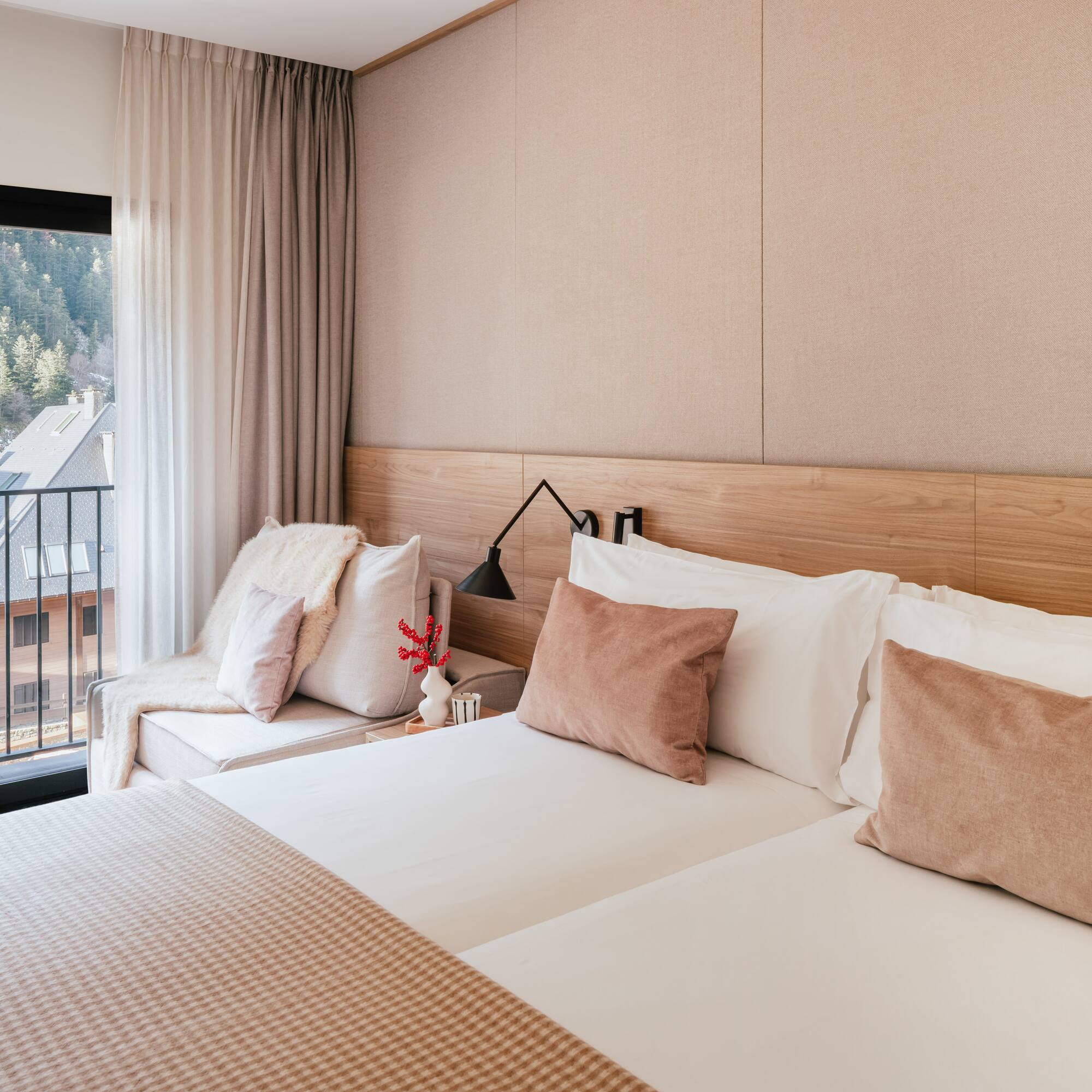 Modern hotel room with mountain view balcony and neutral wooden decor.