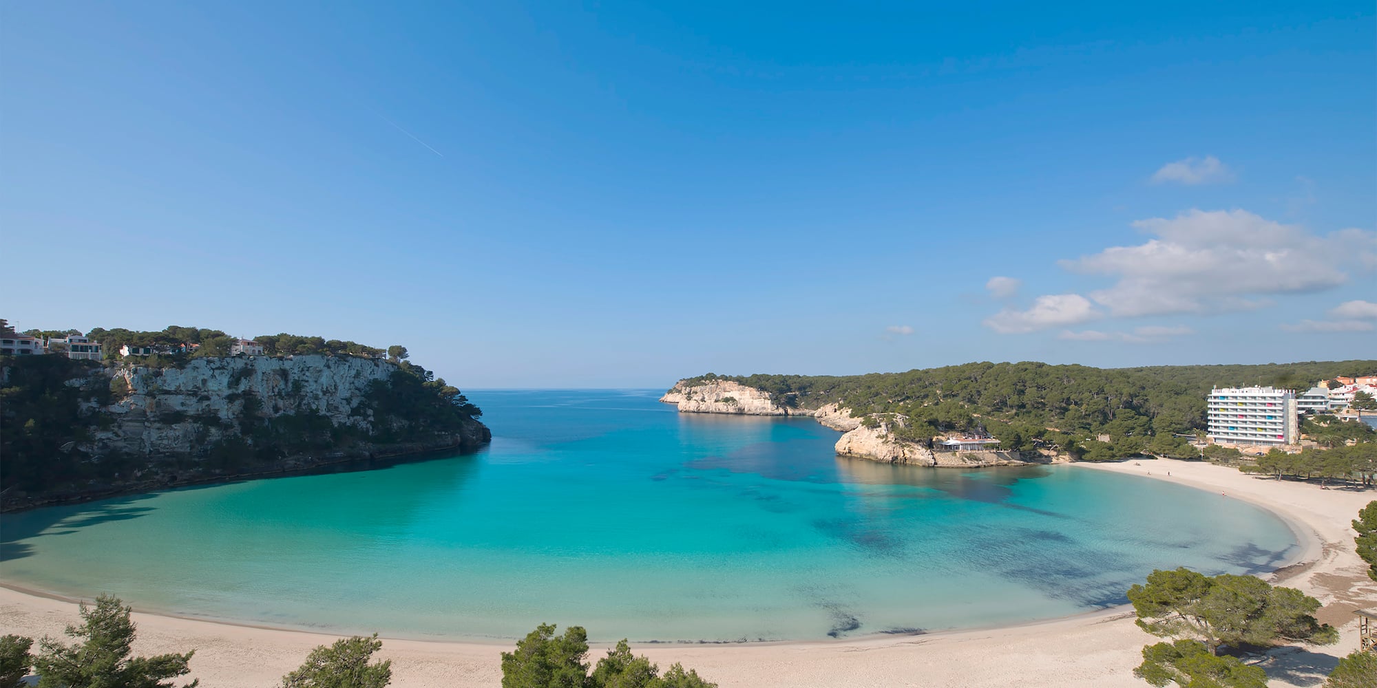 Cala Galdana beach, Menorca: turquoise water, white sand, cliffs, resort.