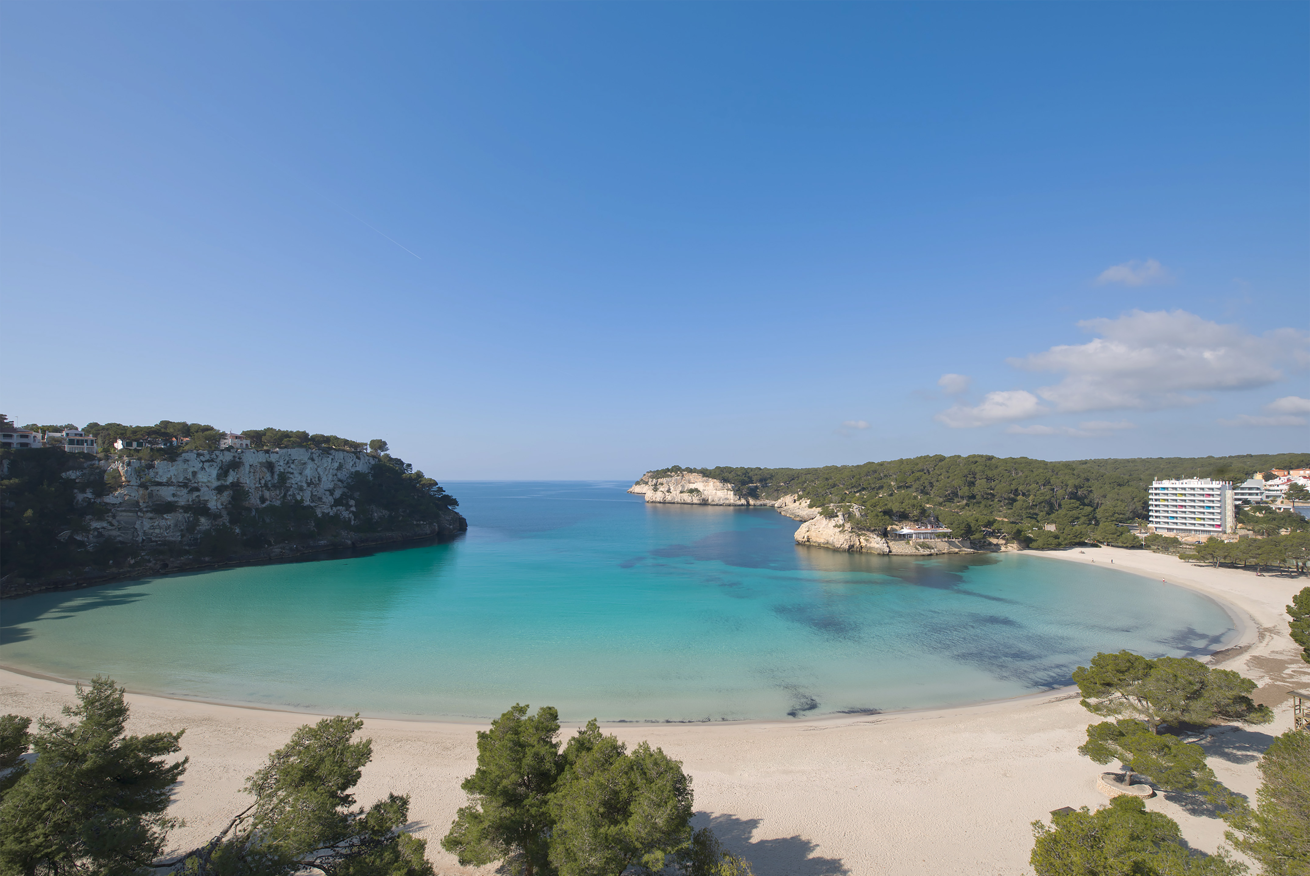 Cala Galdana beach, Menorca: turquoise water, white sand, cliffs, resort.
