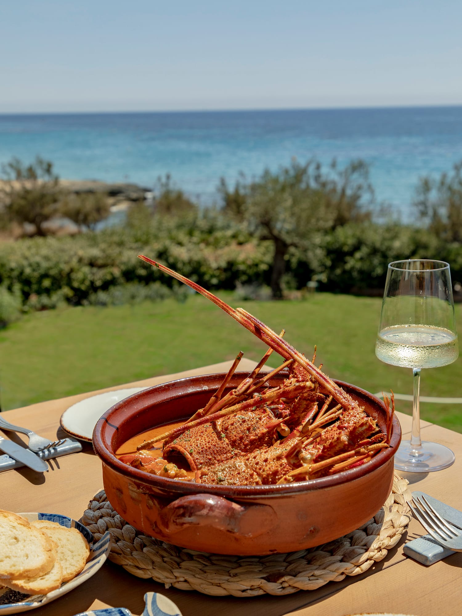 a bowl of lobster on a table with a glass of wine