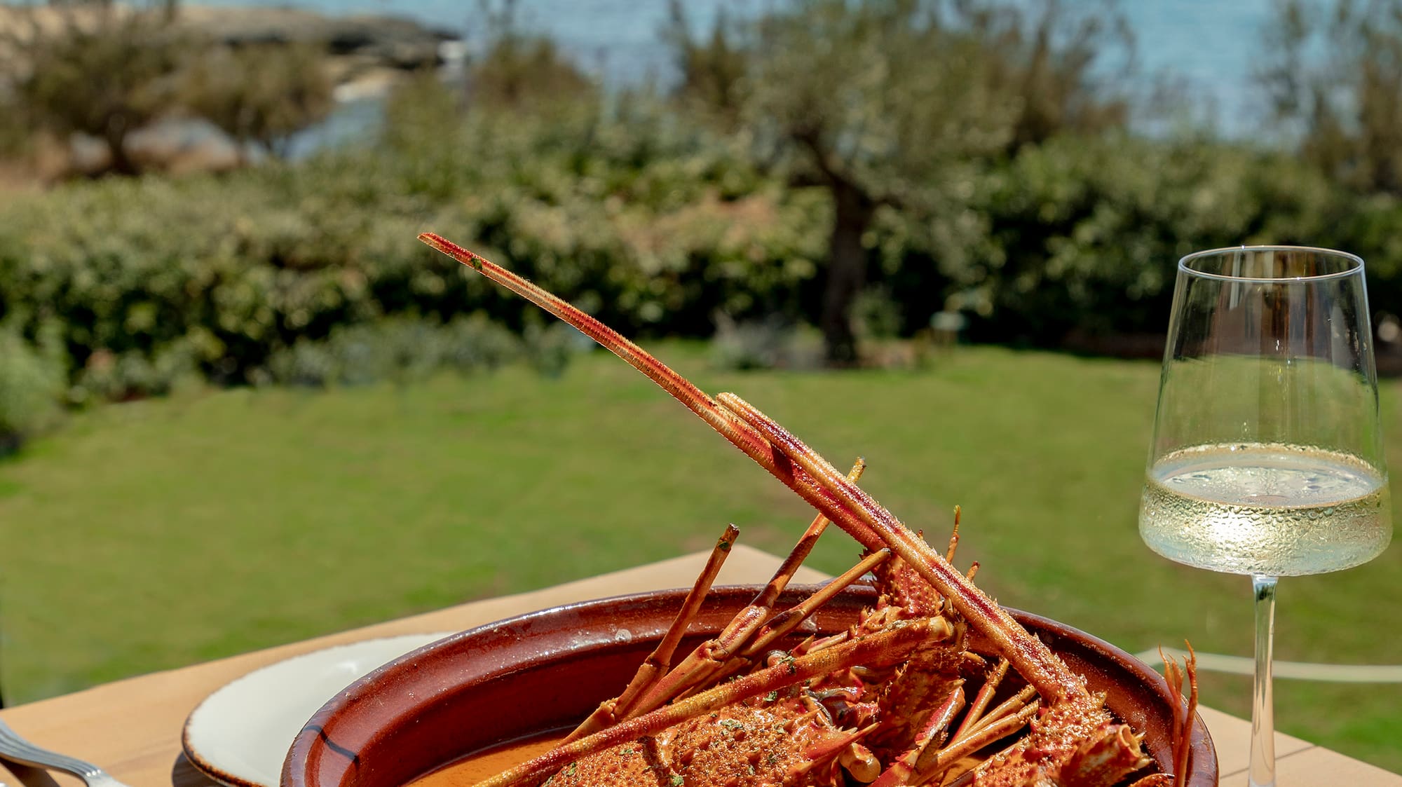 a bowl of lobster on a table with a glass of wine