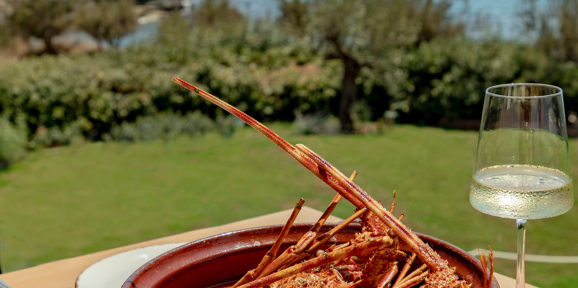 a bowl of lobster on a table with a glass of wine