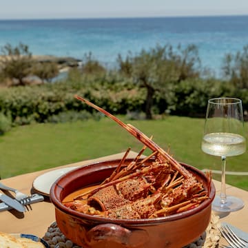 a bowl of lobster on a table with a glass of wine