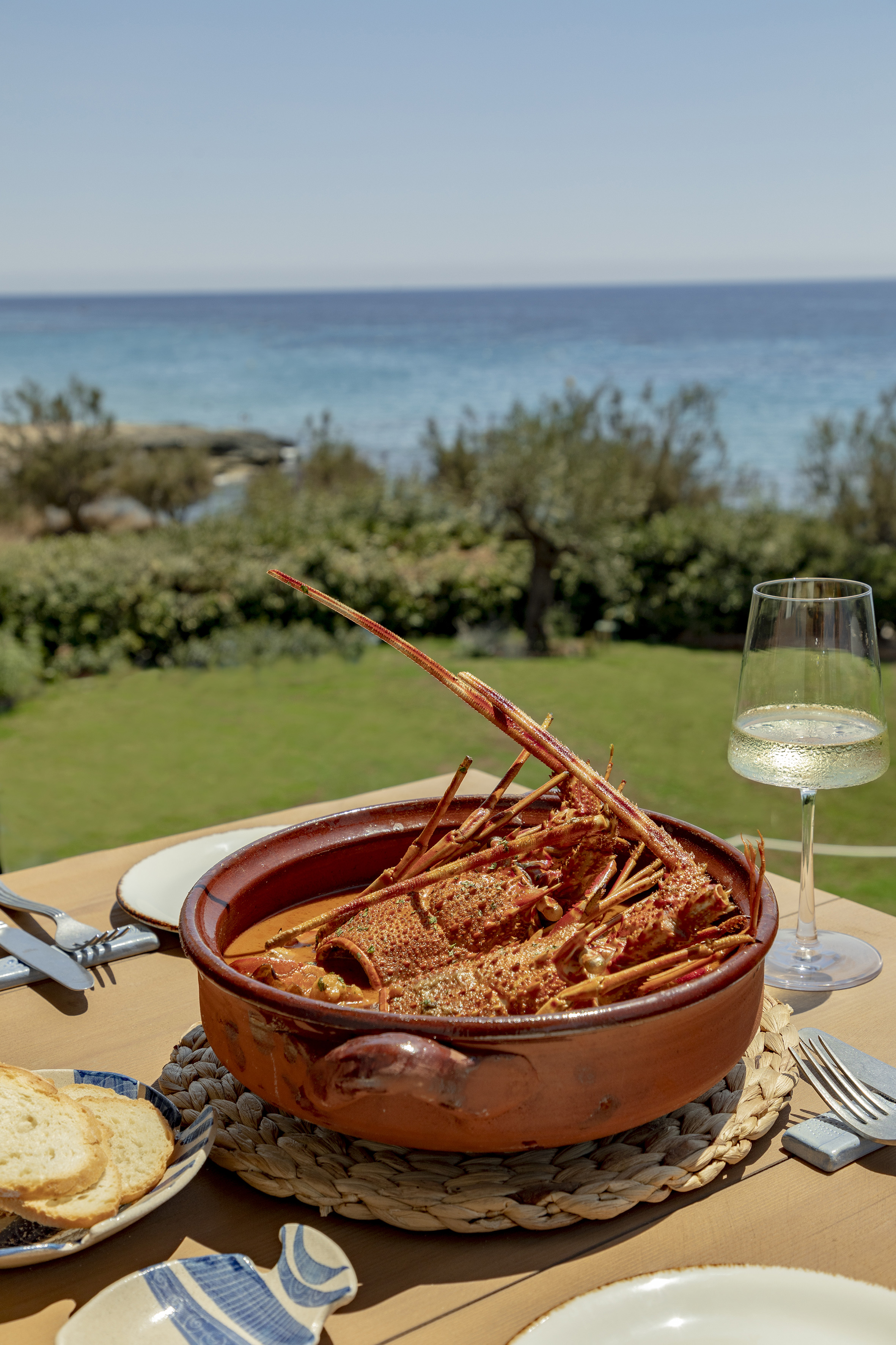 a bowl of lobster on a table with a glass of wine