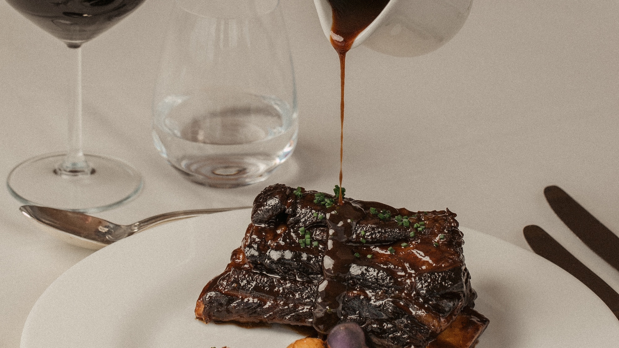 a plate of food with a hand pouring sauce