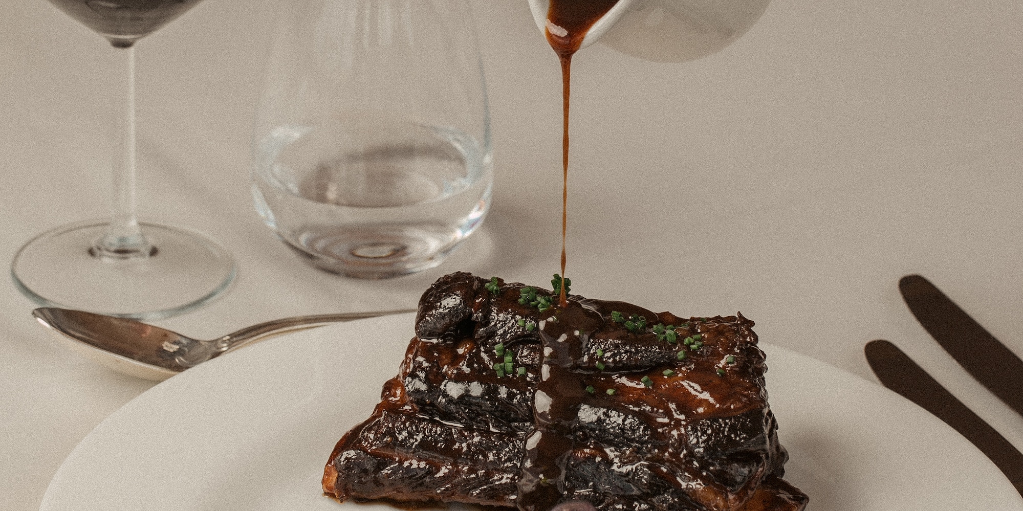 a plate of food with a hand pouring sauce