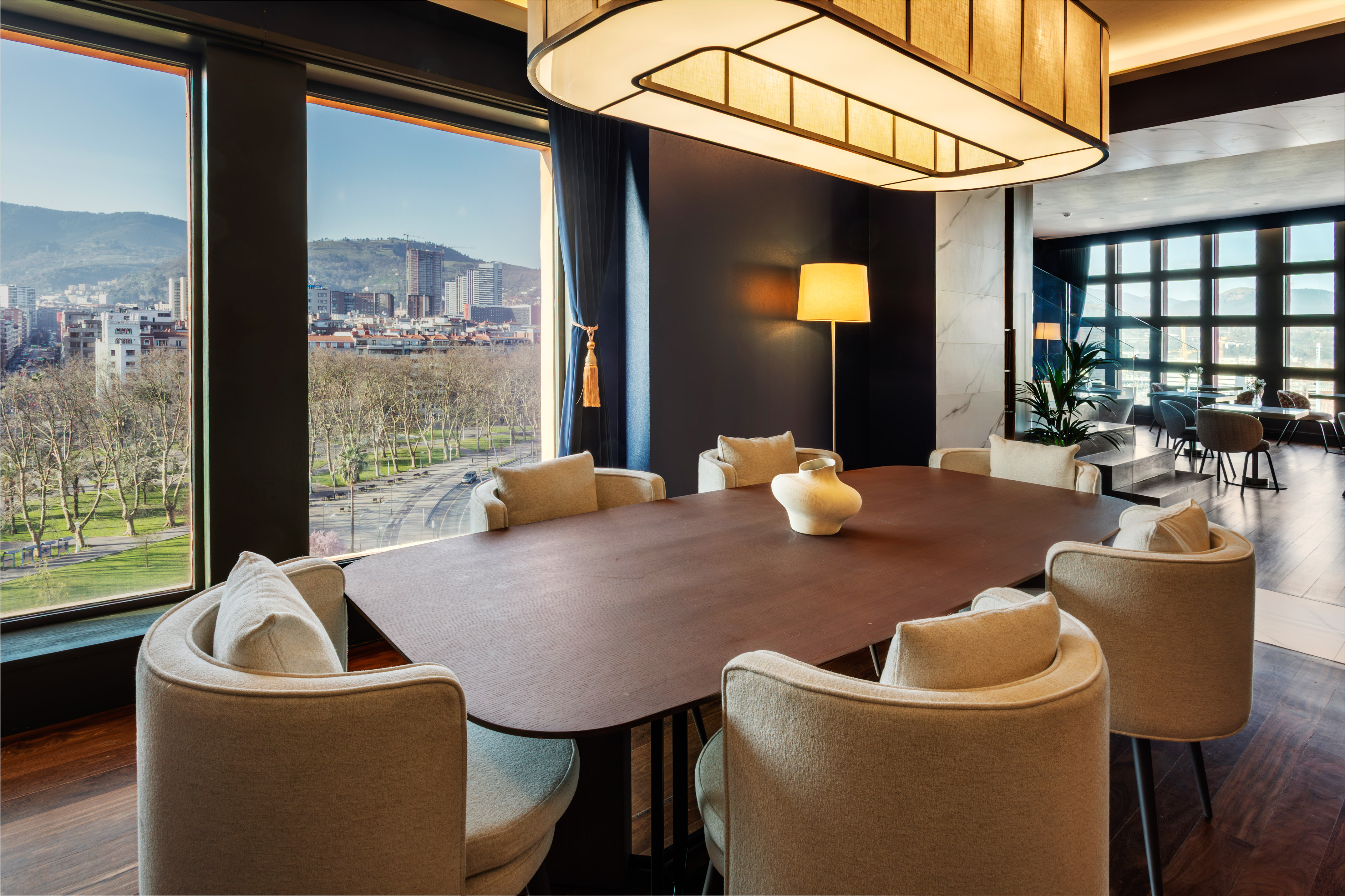 Contemporary meeting room with city view, dark wood table, and cream chairs.
