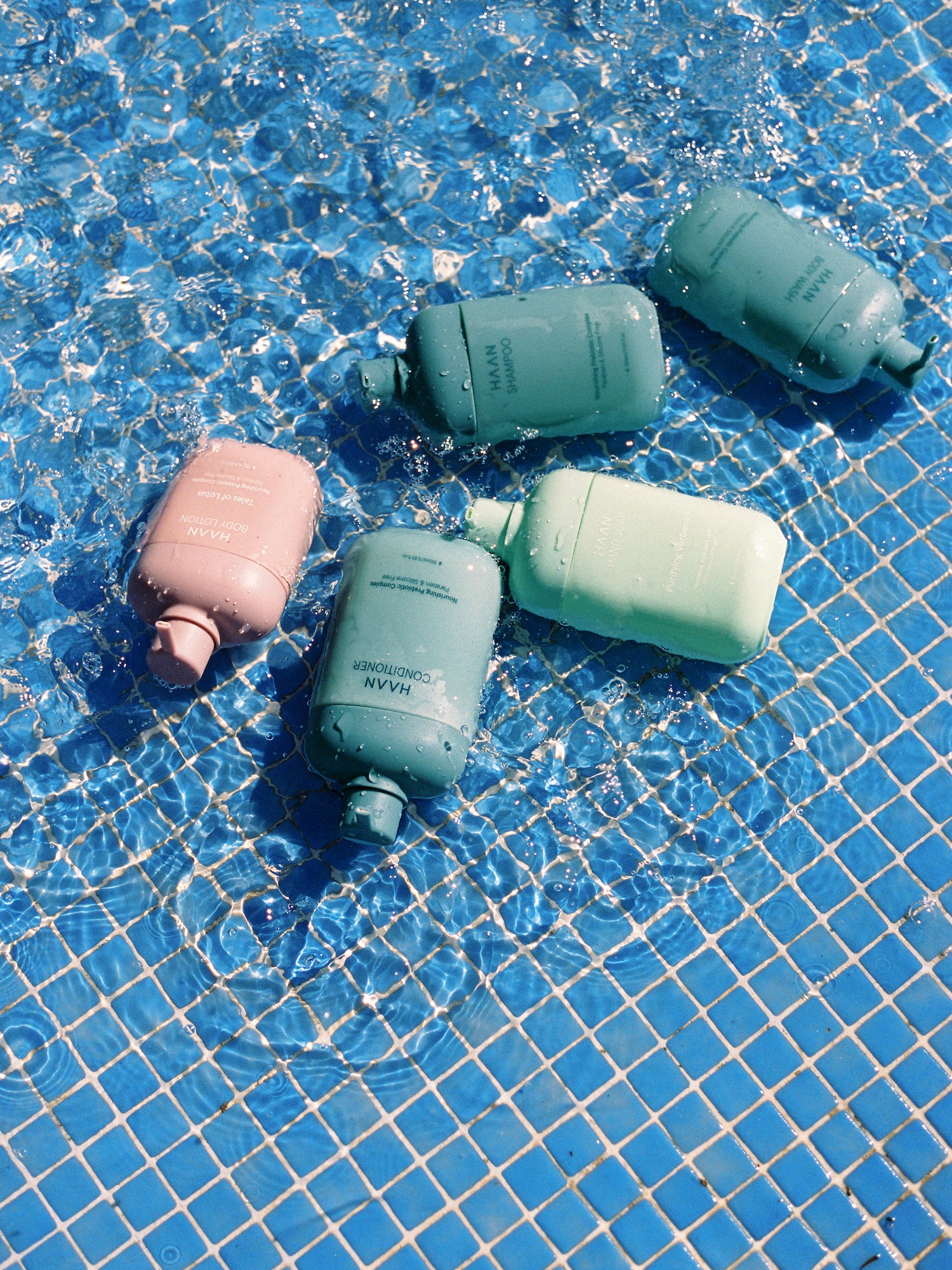 HAAN shampoo, conditioner, body care products in a blue tiled pool.