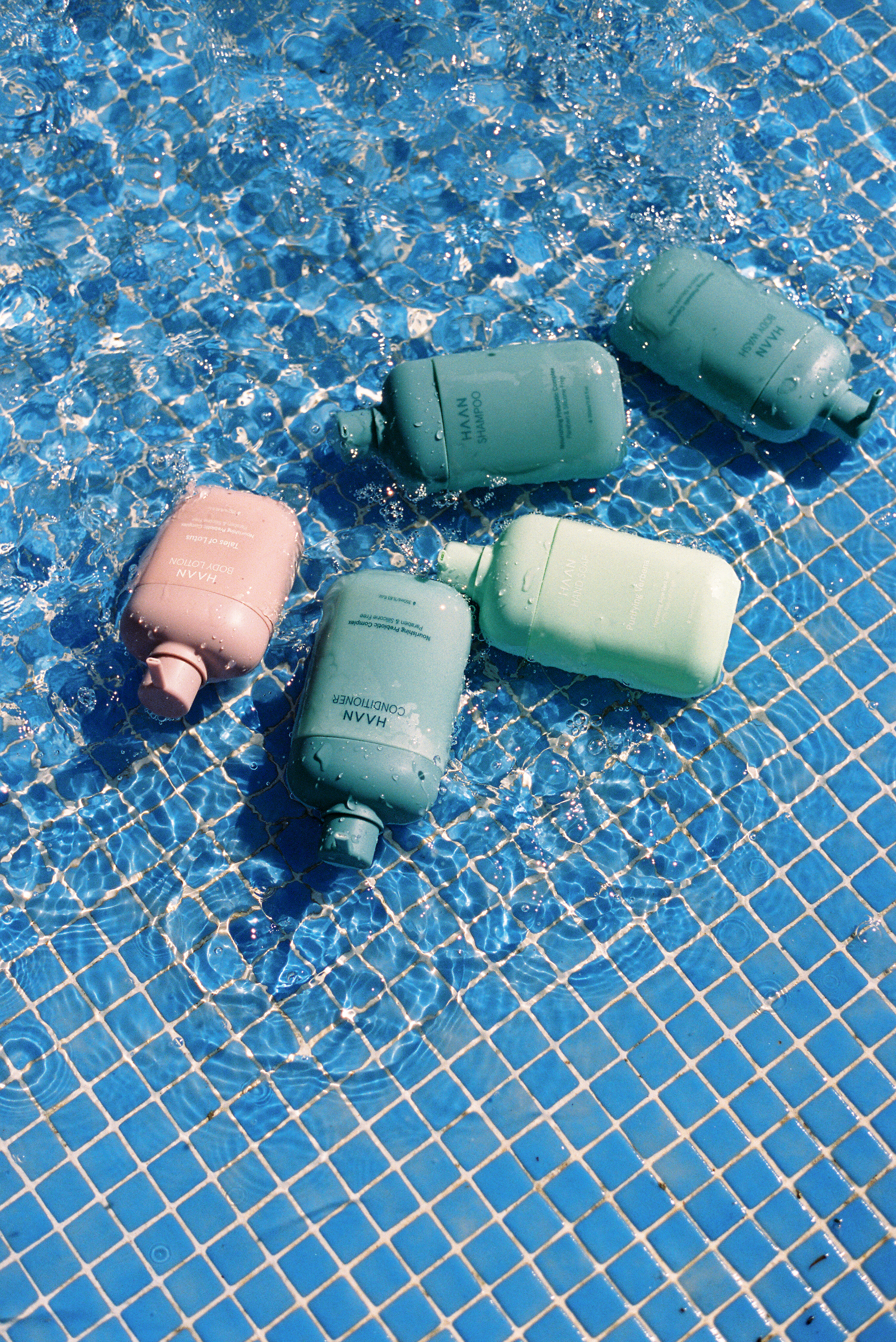 HAAN shampoo, conditioner, body care products in a blue tiled pool.