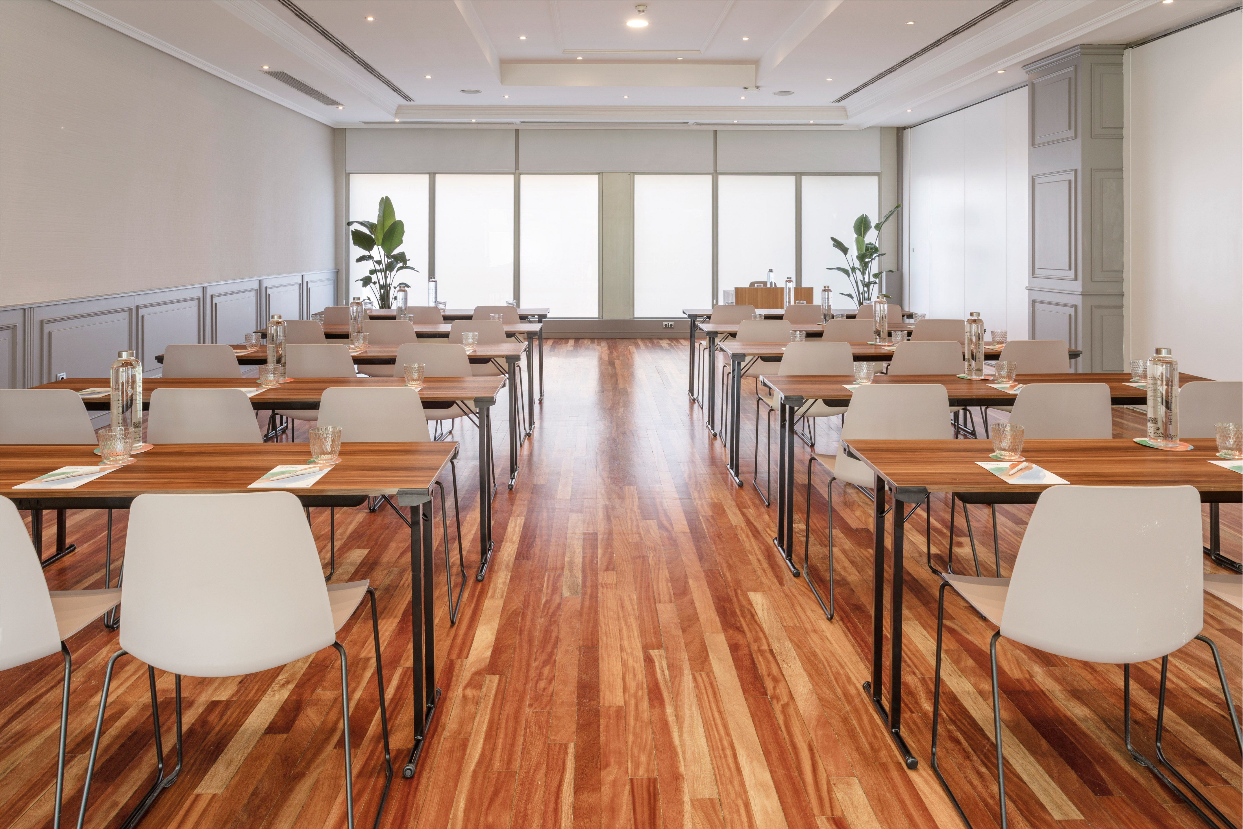 Modern conference room with classroom setup, wooden tables and light chairs.
