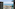 Sunny beach and ocean view from modern hotel balconies with palm trees.