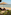 Tropical resort beach with lounge chairs, umbrella, ocean, and Balinese statue.