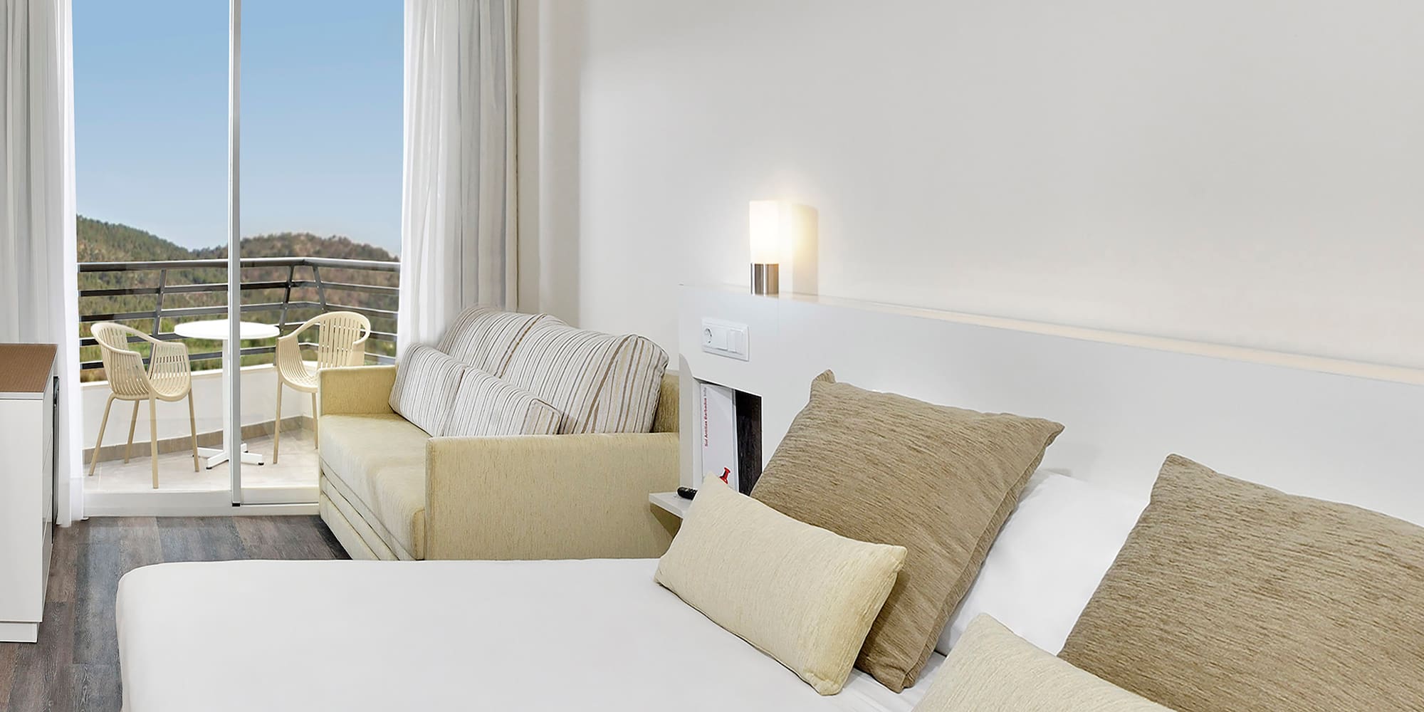 a bed with pillows and a couch in a room with a balcony