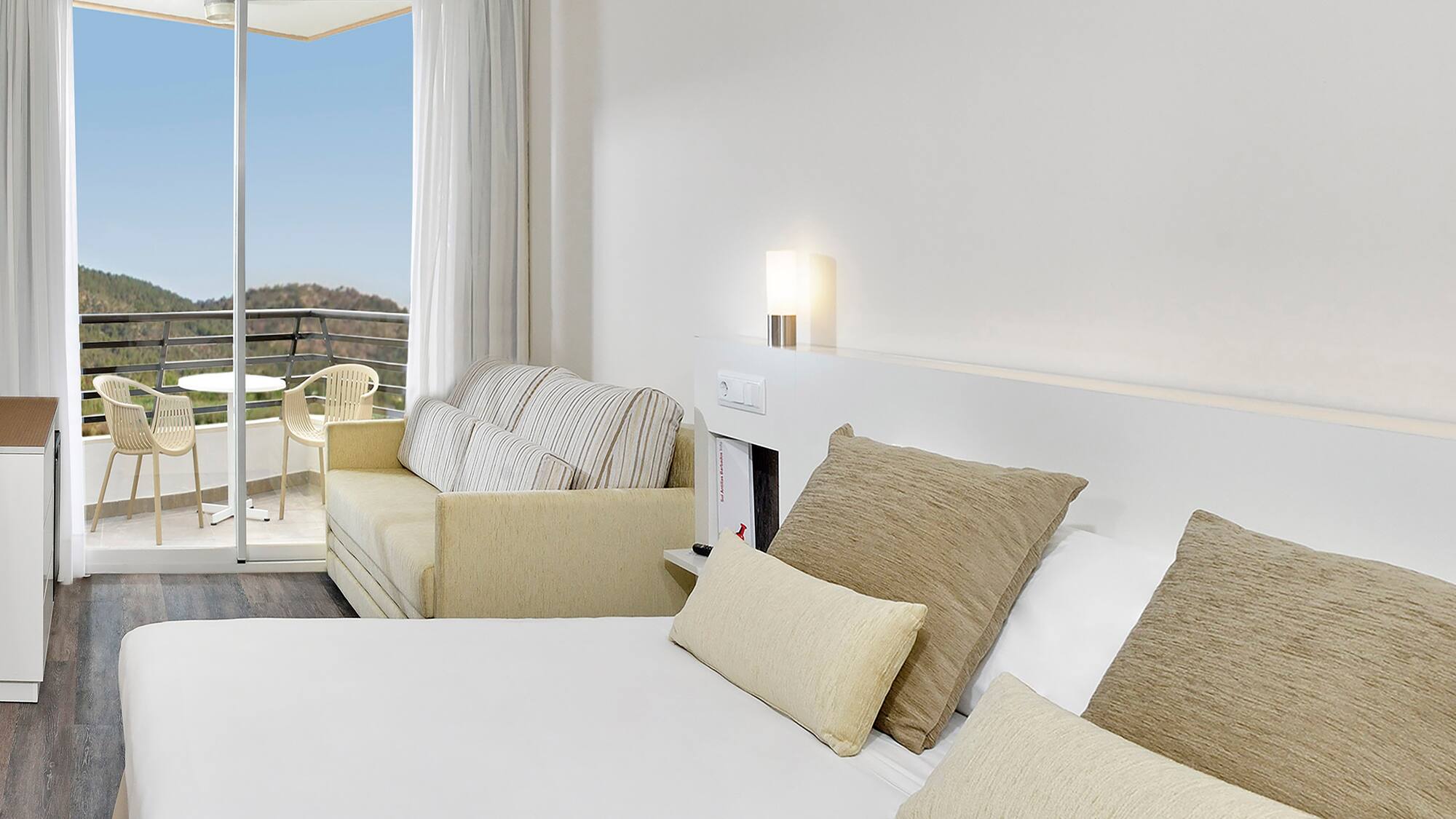 a bed with pillows and a couch in a room with a balcony