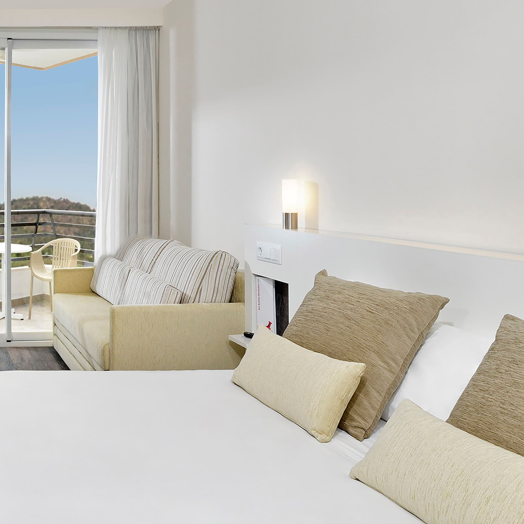 a bed with pillows and a couch in a room with a balcony