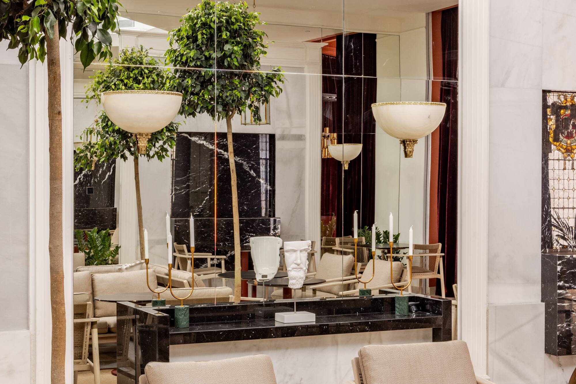 Modern lounge interior with indoor trees, mirrored walls, and marble accents.