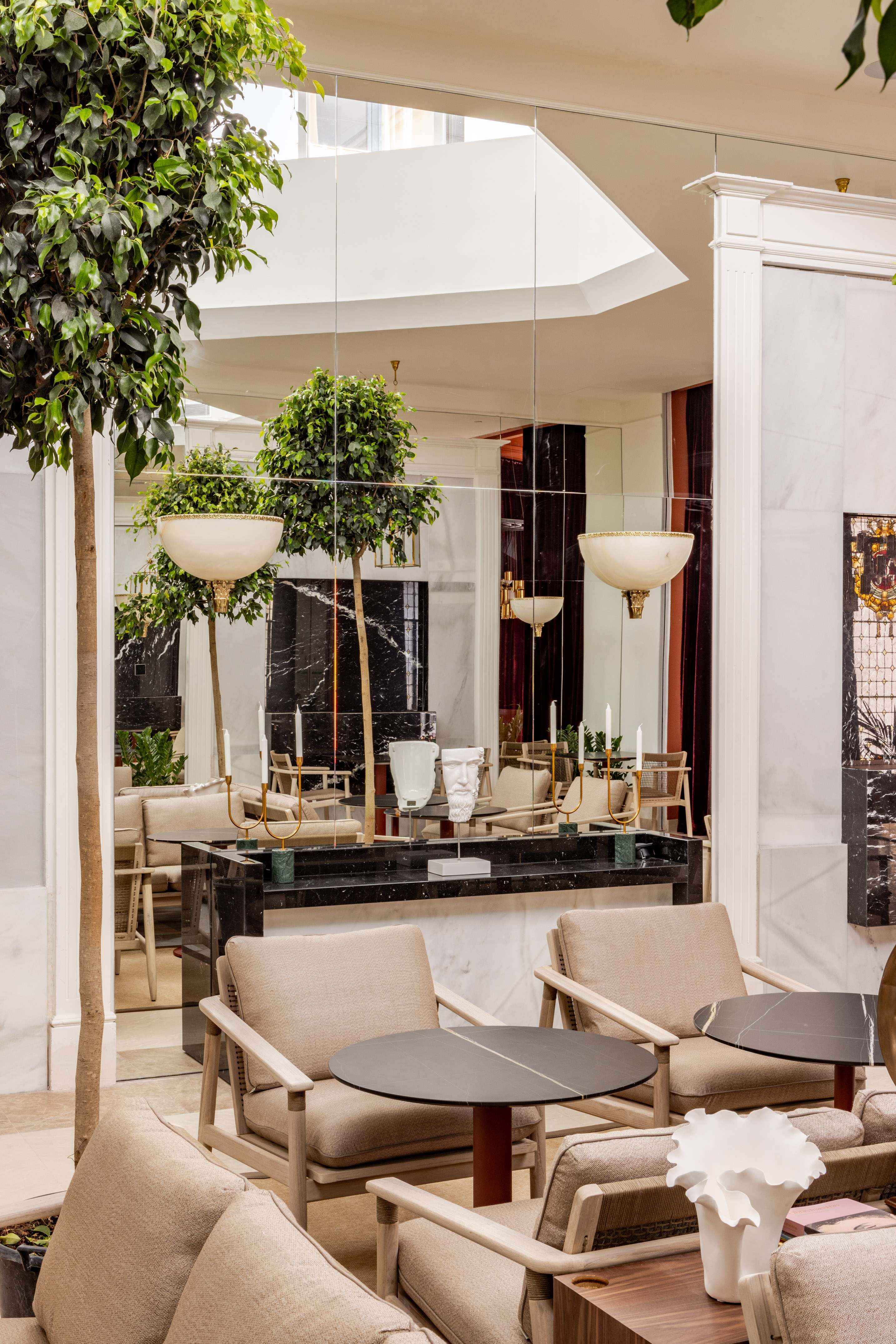 Modern lounge interior with indoor trees, mirrored walls, and marble accents.