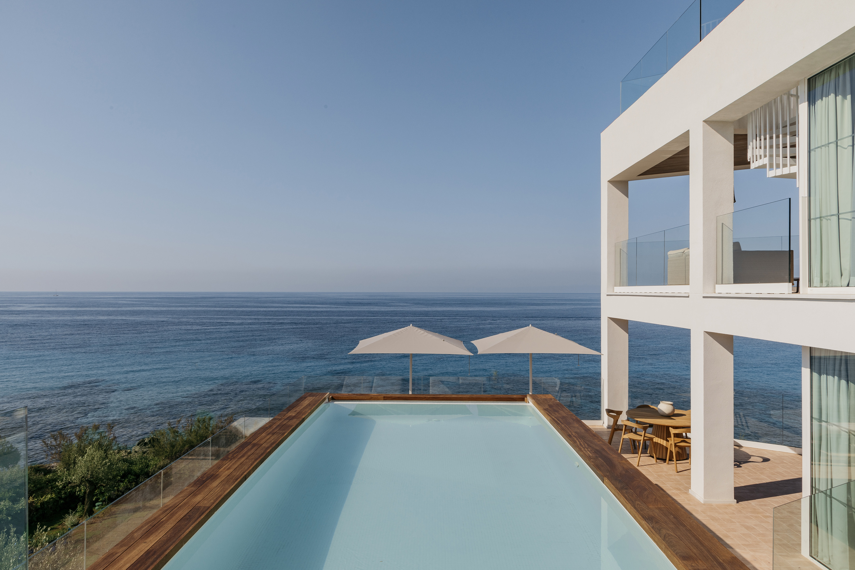 Modern oceanfront villa with infinity pool, sea view, and outdoor dining.