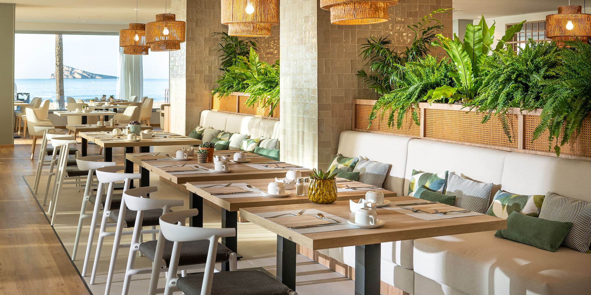 a long table with white chairs and plates and a white cushioned couch