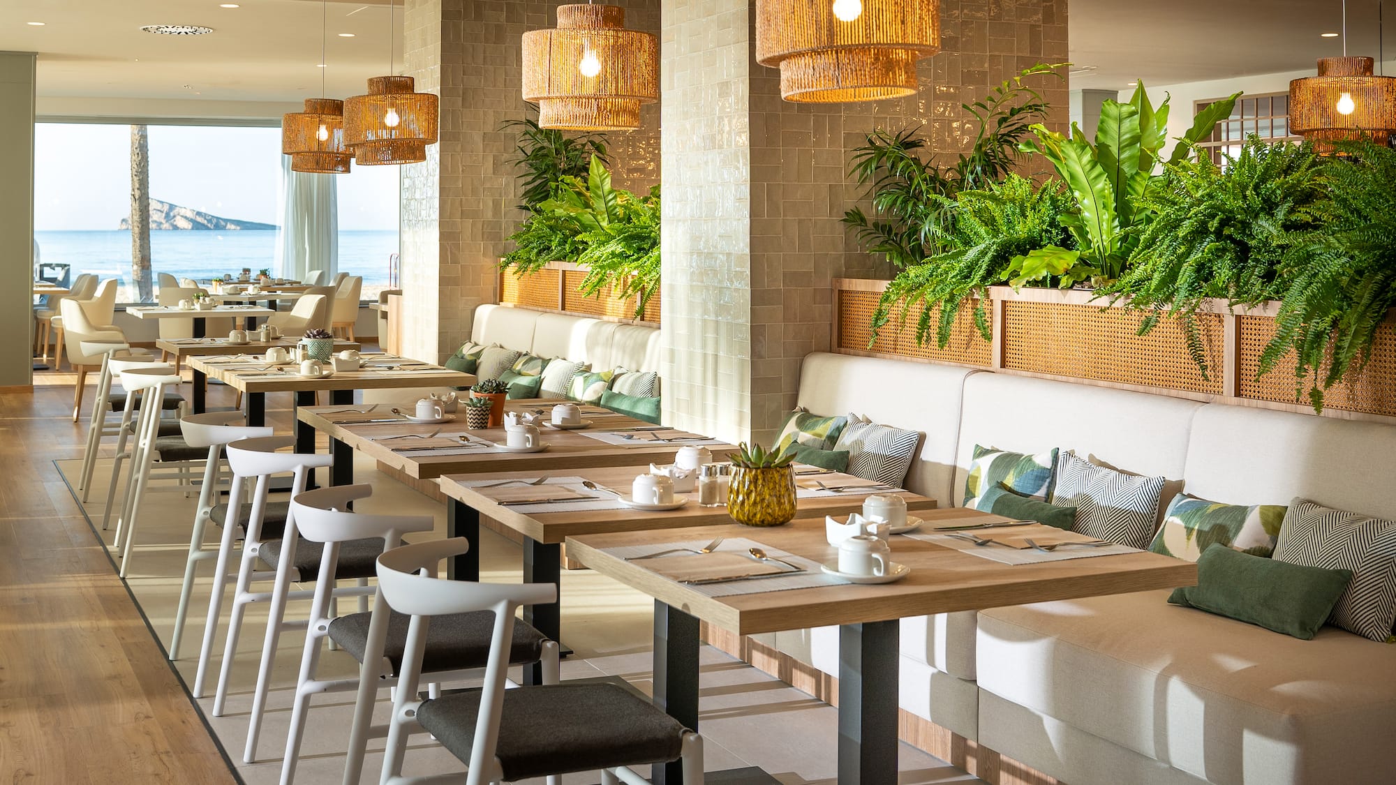 a long table with white chairs and plates and a white cushioned couch