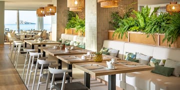 a long table with white chairs and plates and a white cushioned couch