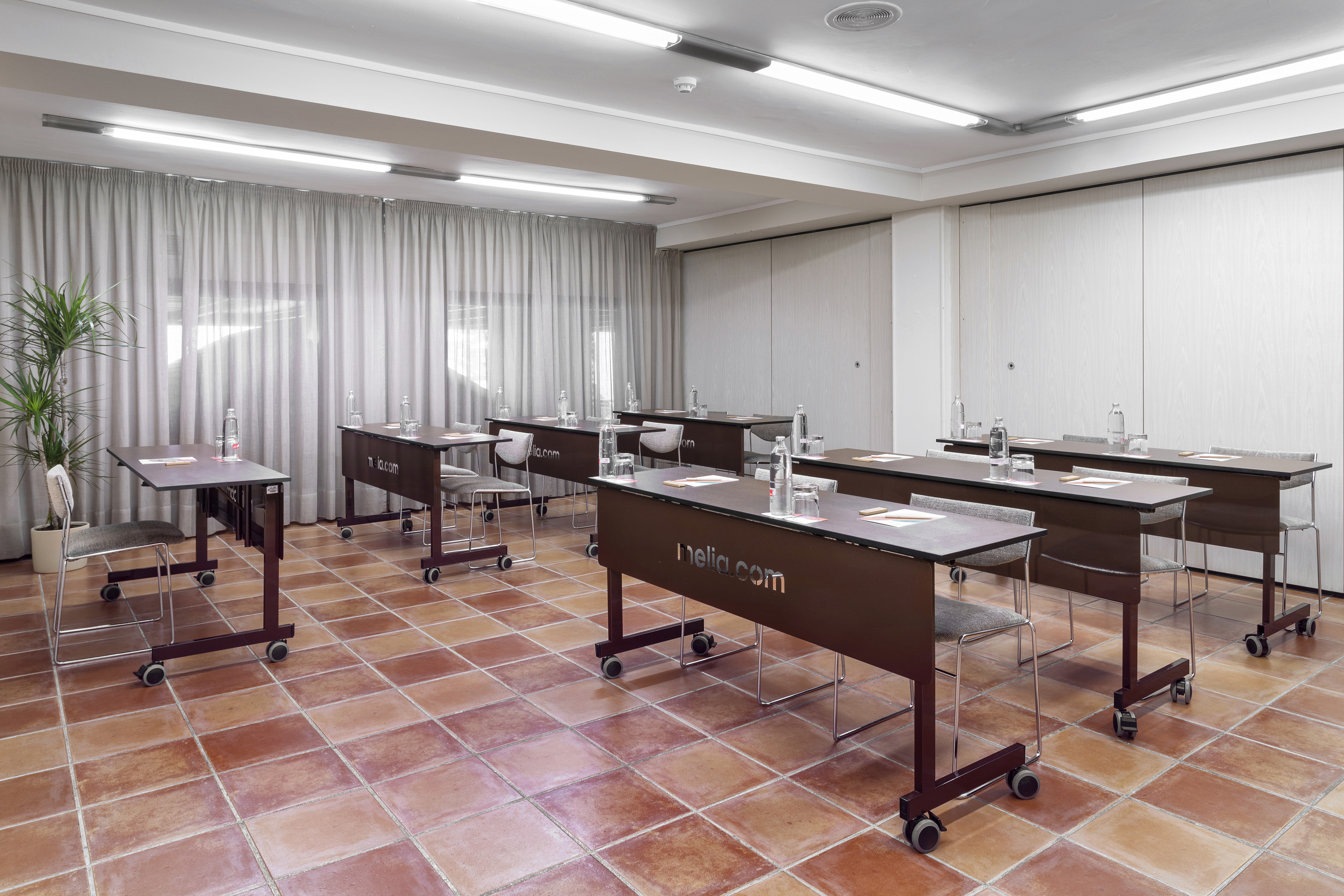 Meliá conference room with individual tables, chairs, water bottles, terracotta floor.