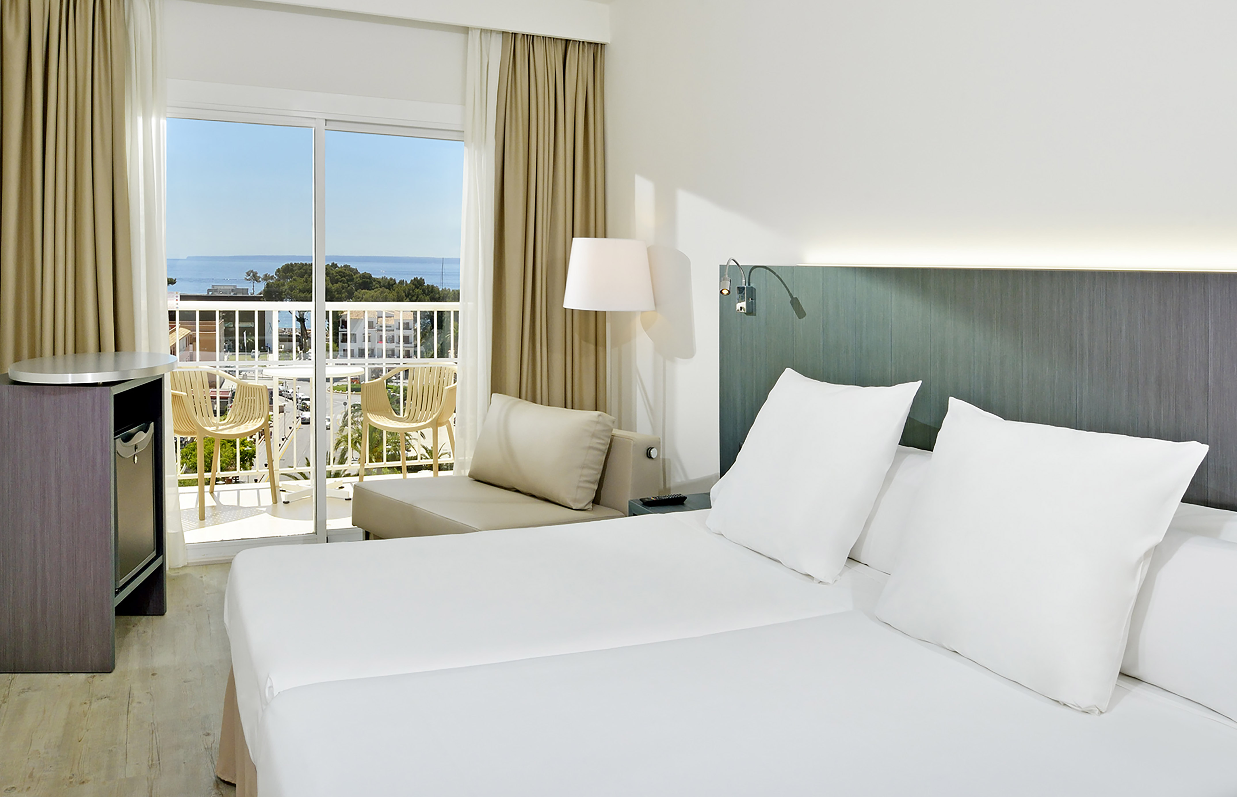 Hotel room with twin beds, private balcony, and ocean view.