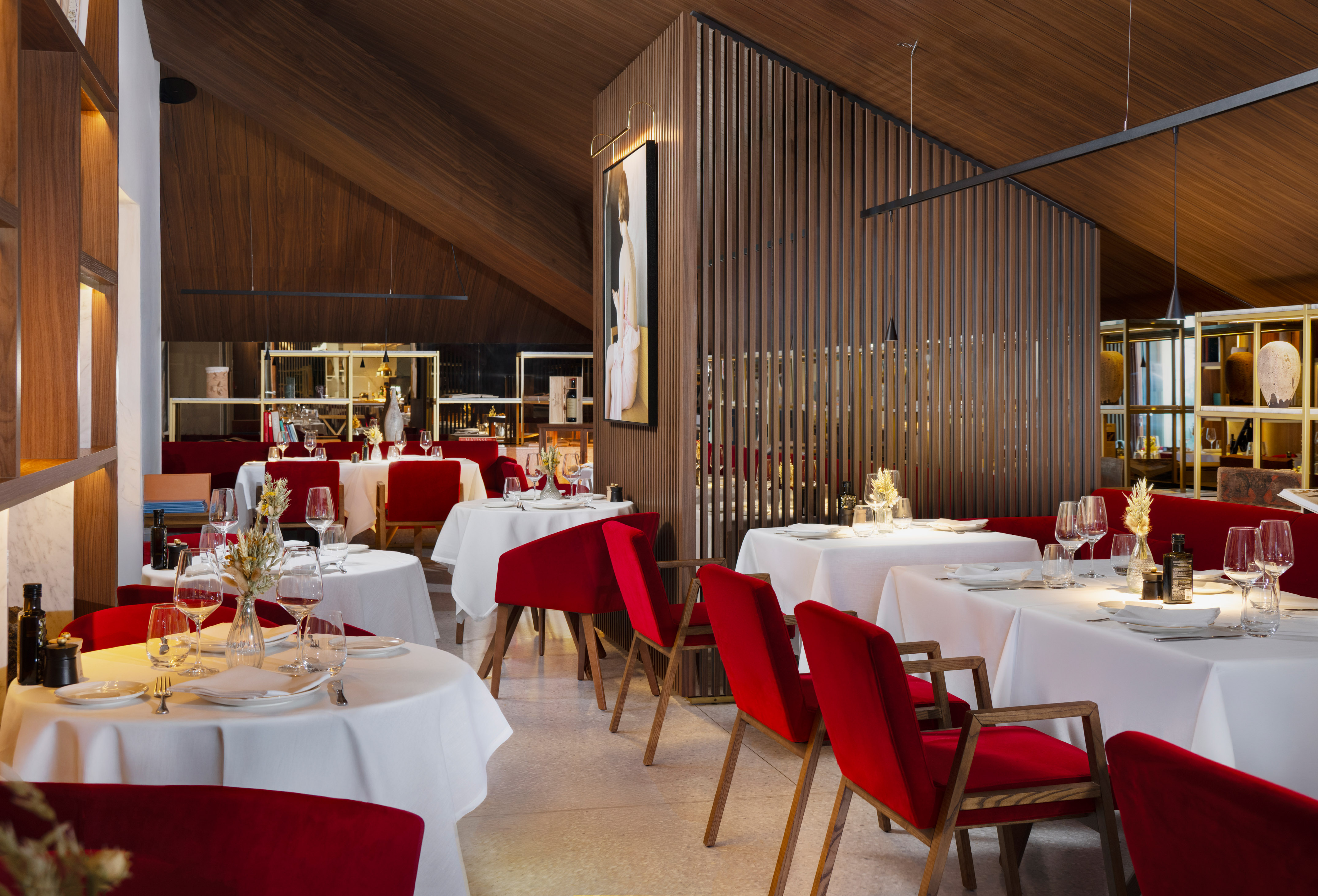 Elegant restaurant interior with red velvet chairs, white tables, and wood paneling.