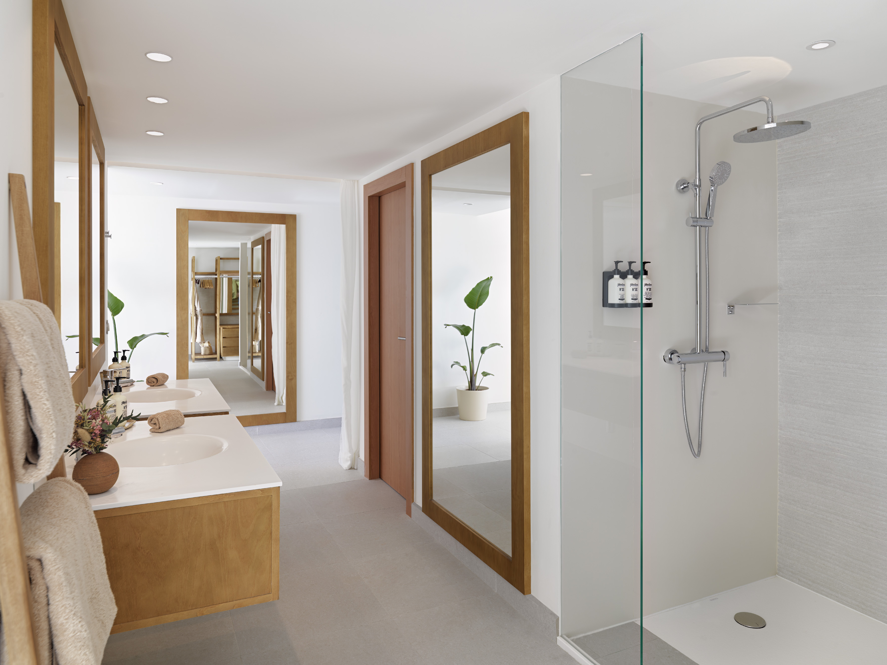 Bright modern bathroom with double sink, glass shower, and large wooden mirrors.