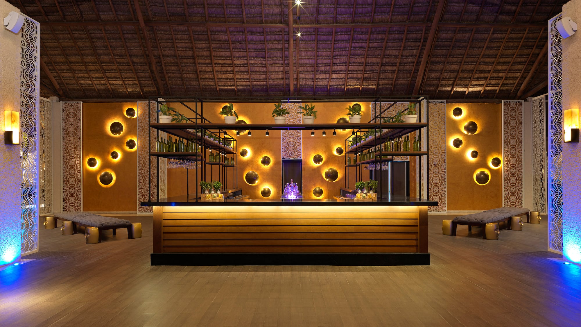 Luxury resort bar with thatched roof, glowing circular wall lights, and modern decor.