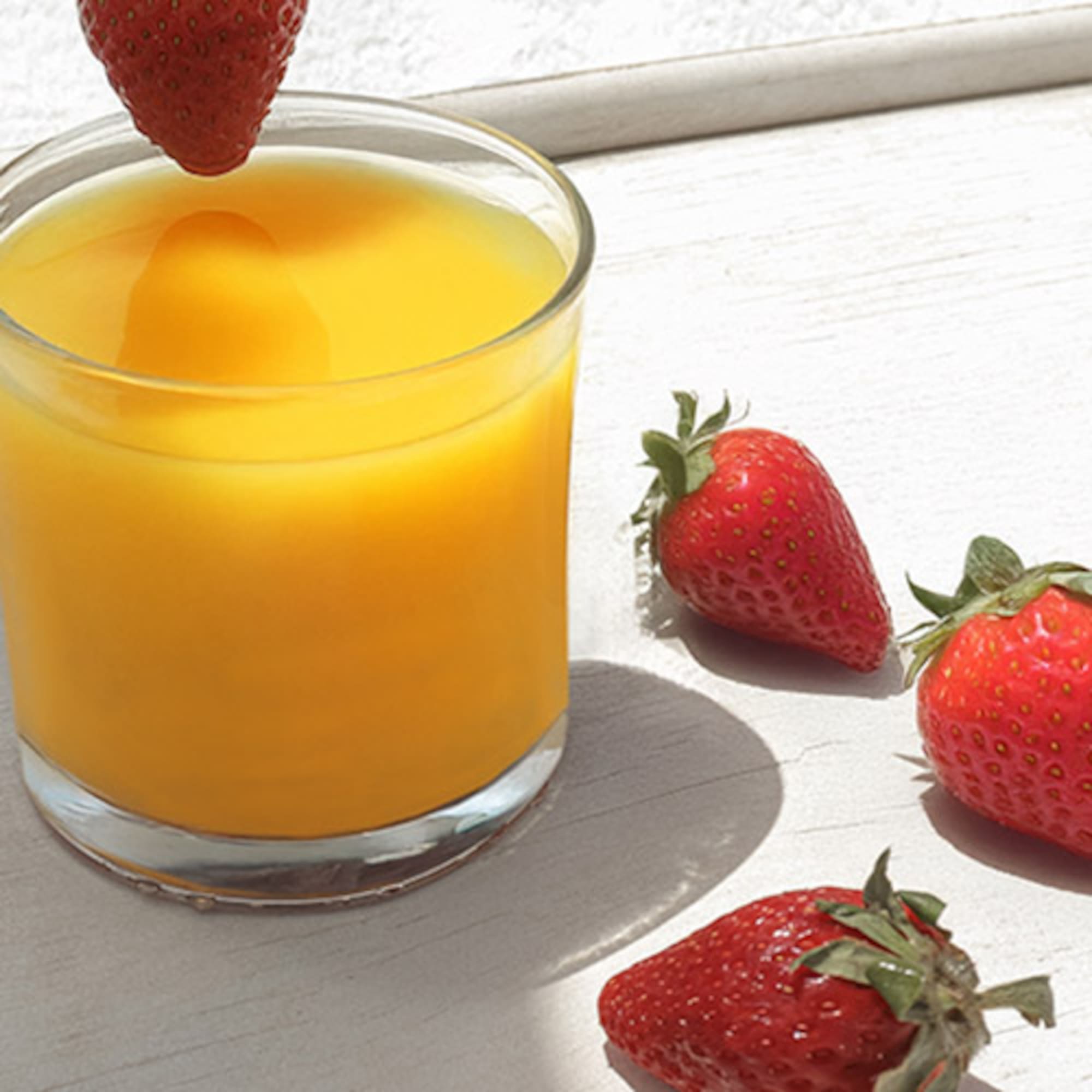 a glass of orange juice and strawberries